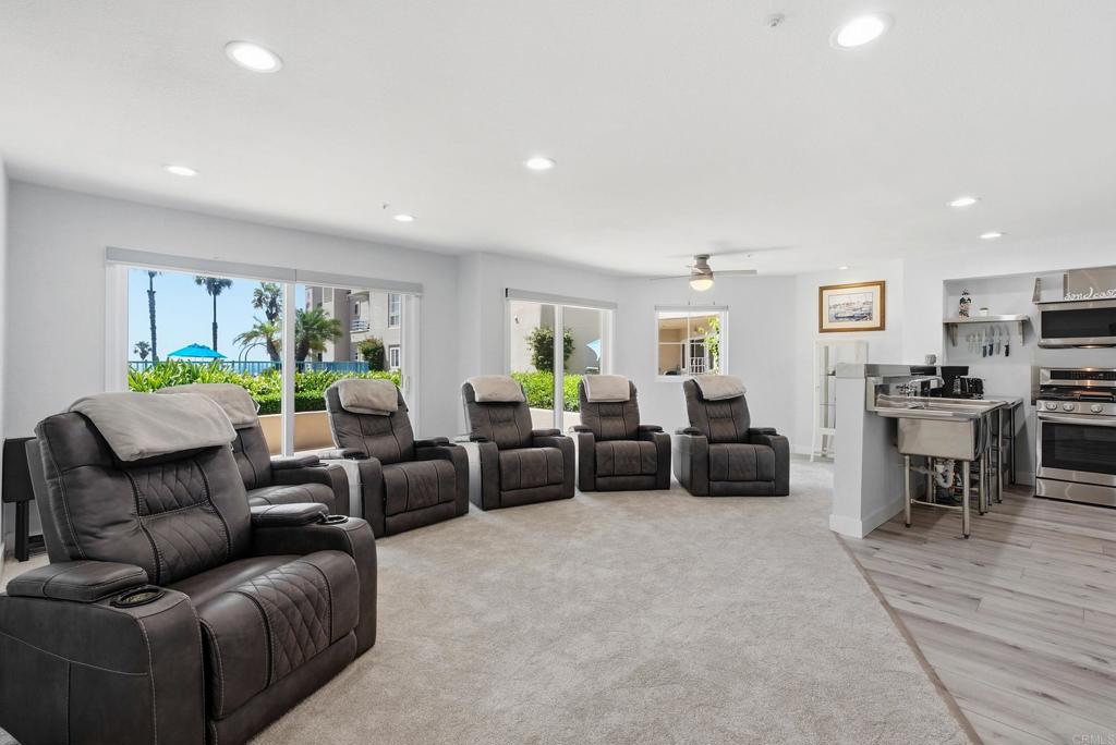 Living room with leather recliners, large coastal-facing windows, and an open kitchen.