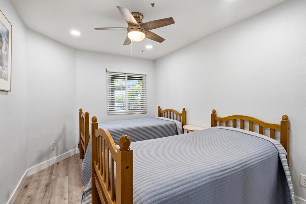 Bedroom with two wooden twin beds, gray striped bedding, and a ceiling fan.