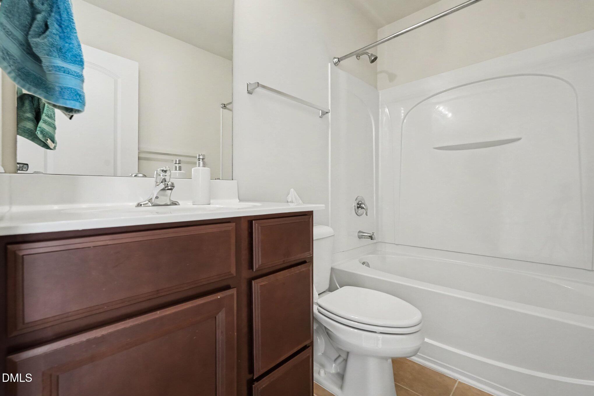 Bathroom with dark wood vanity, white toilet, and bathtub with a molded shower surround.