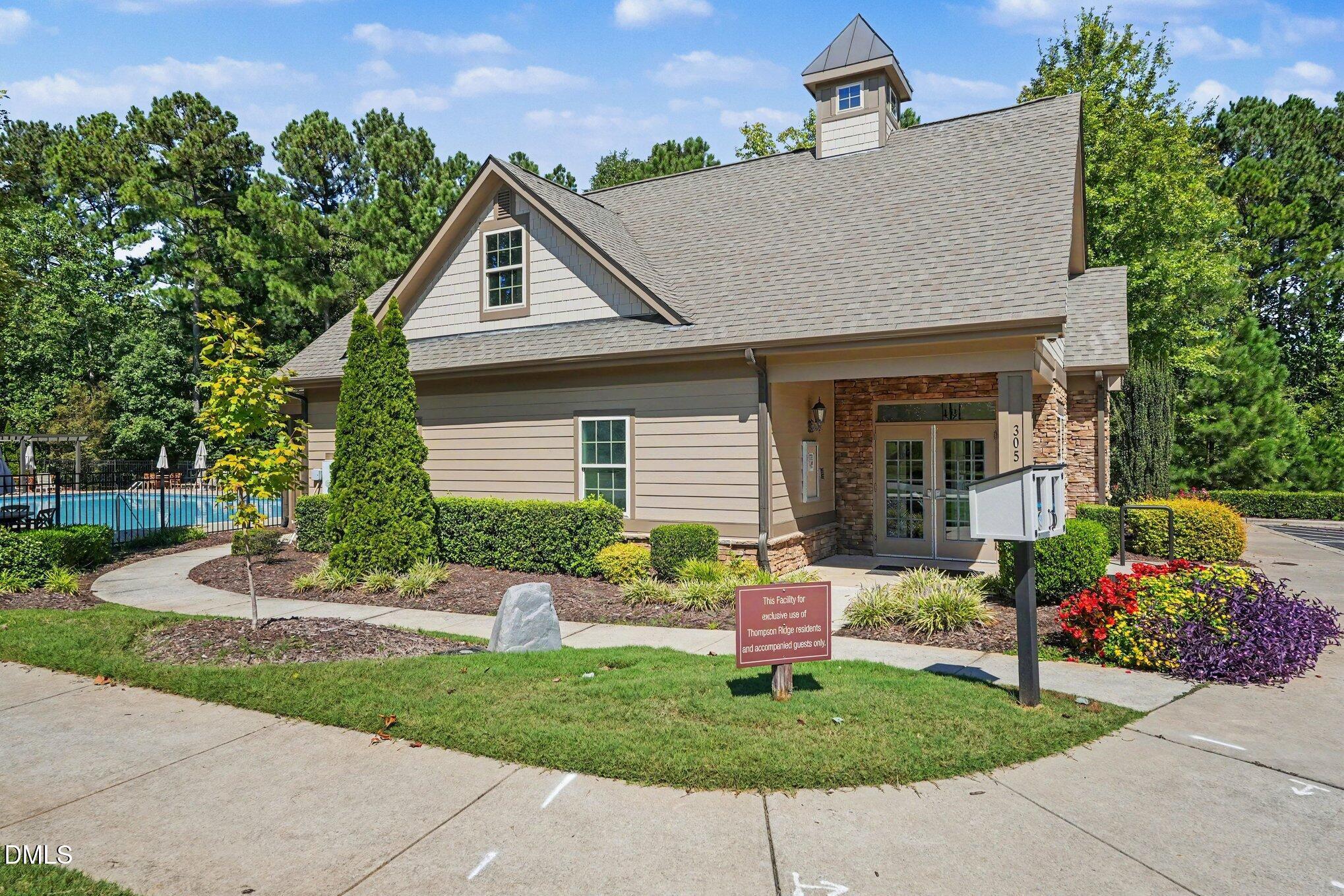 Community clubhouse with stone entry, landscaped grounds, and a fenced swimming pool.