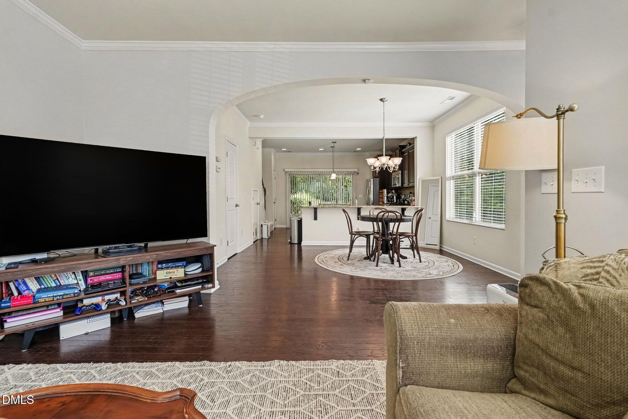 Living room with dark hardwood floors and an arched opening to the dining area and kitchen.