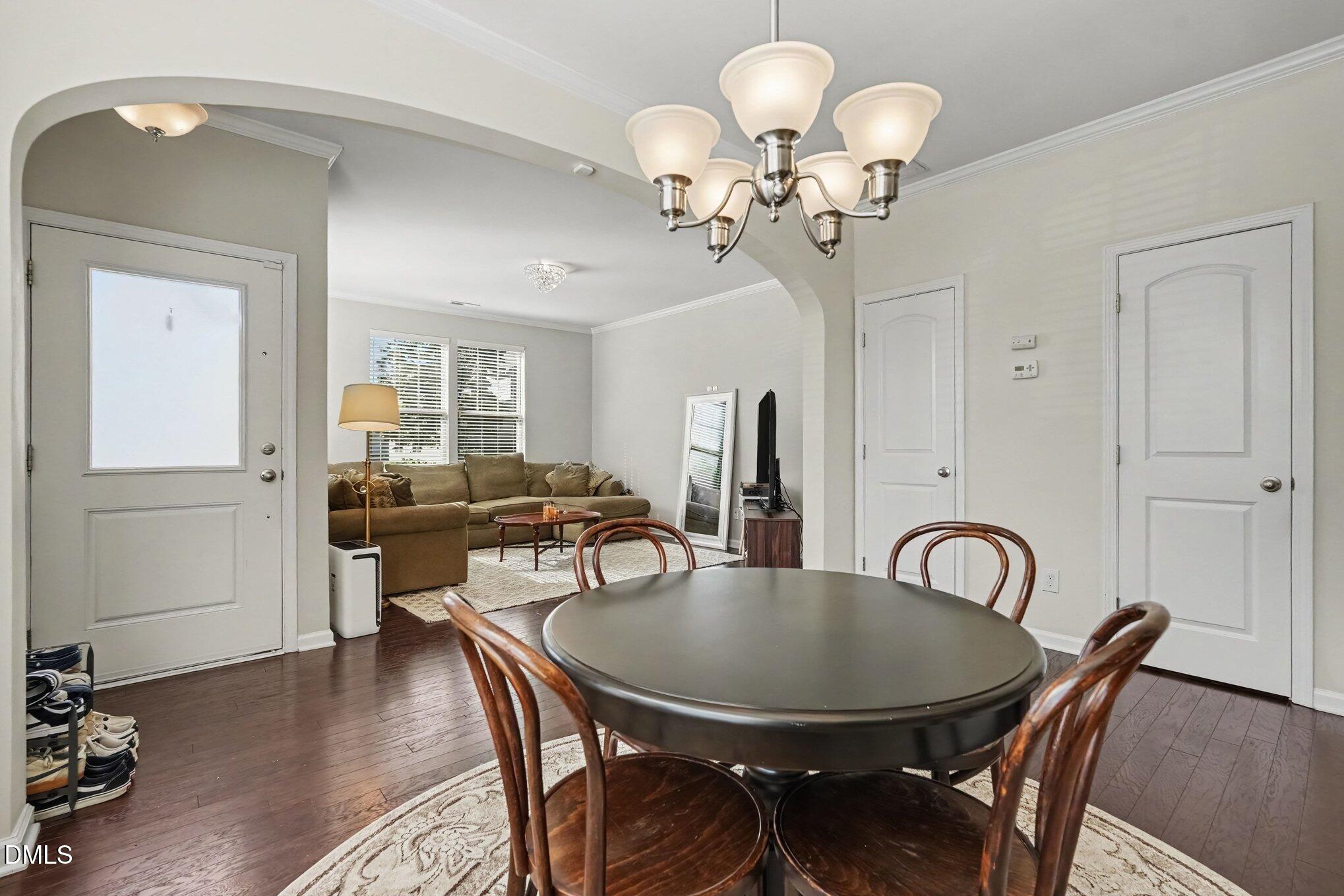 Dining room with an oval table and wooden chairs opening onto a living room with a brown sectional.