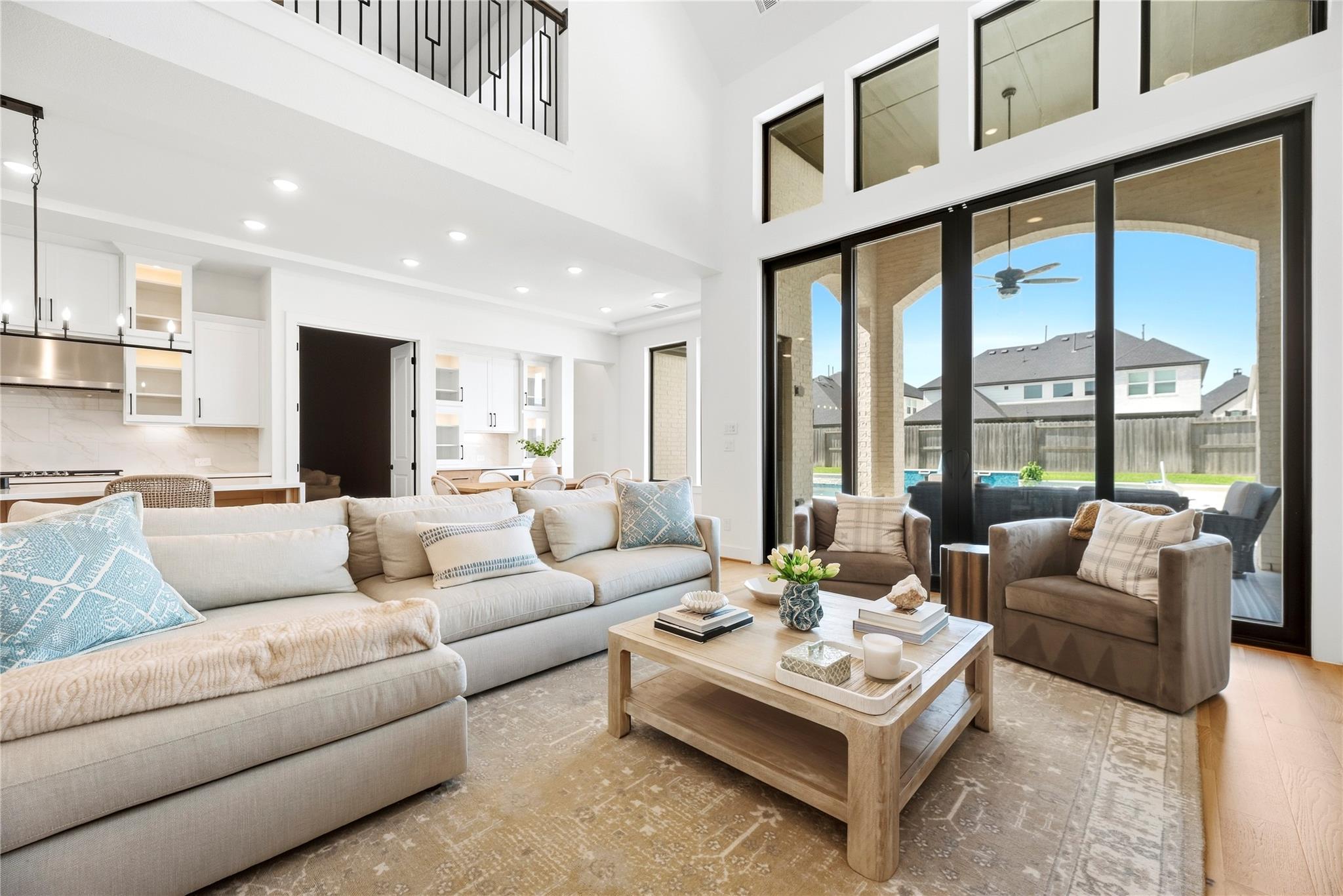 Living room with a cream sectional, open kitchen, and sliding doors to a covered patio and pool.