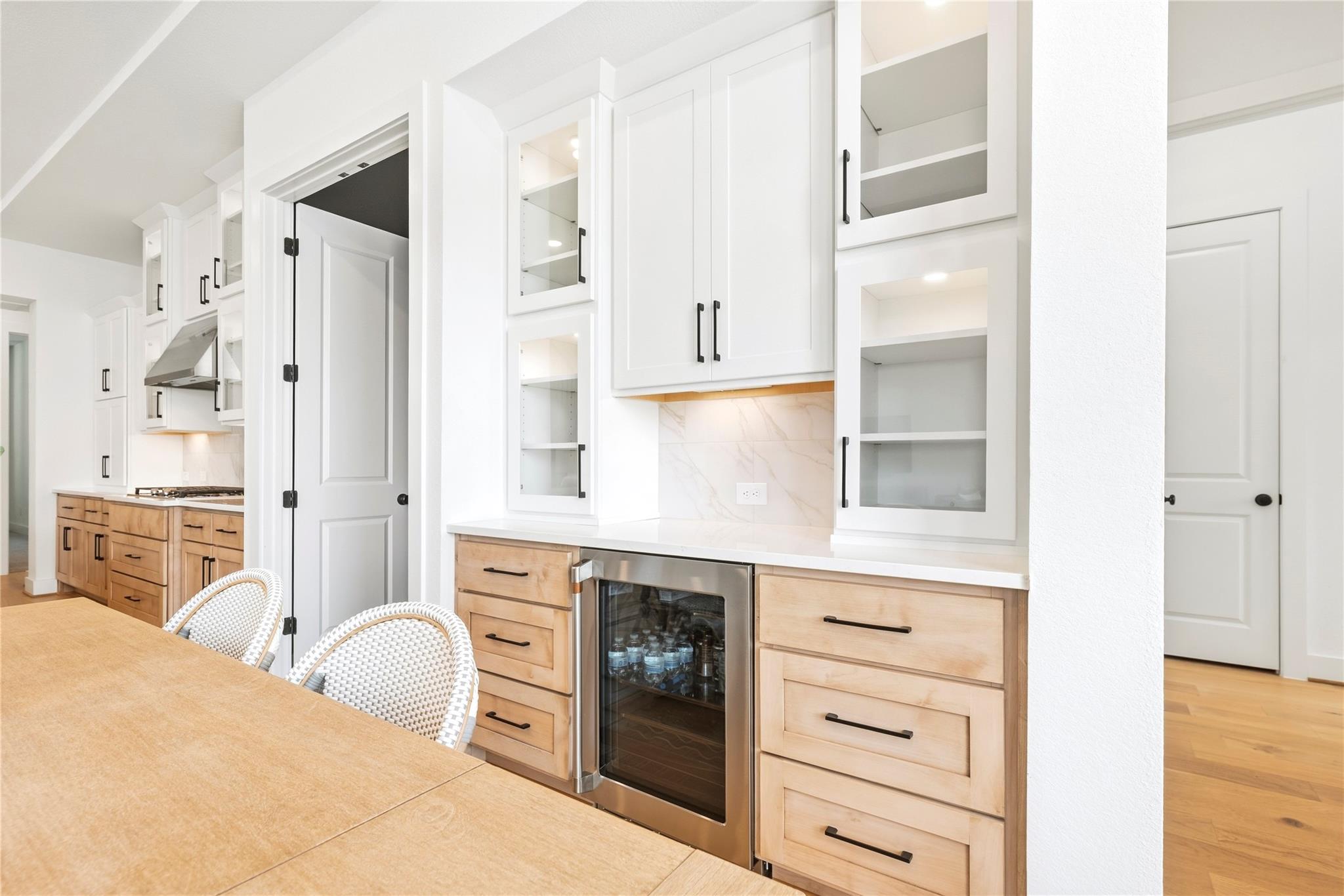 Bright kitchen with light wood cabinetry, white cabinets, and a built-in beverage refrigerator.