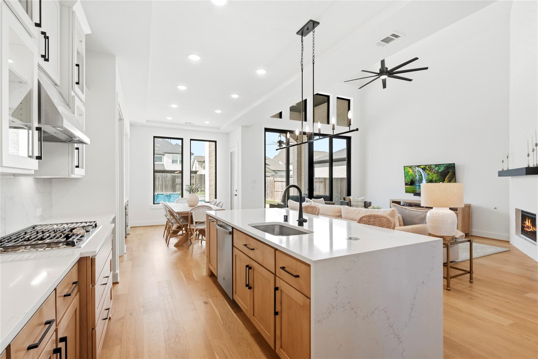 Open kitchen and living area with a large quartz island, warm wood cabinetry, and a fireplace.