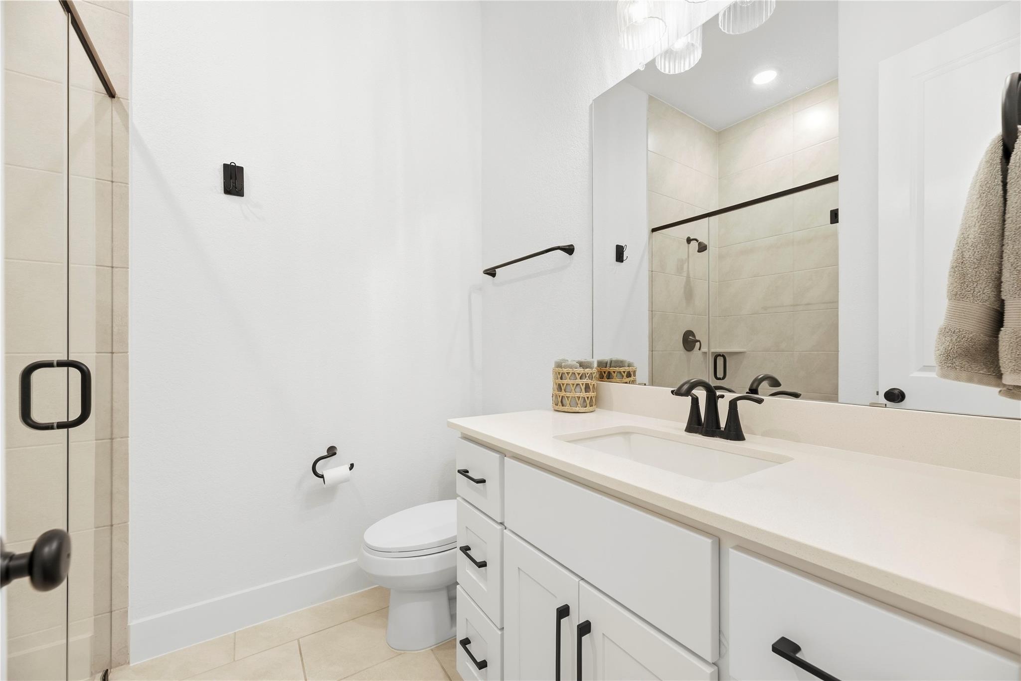 Bathroom with a white vanity, black fixtures, and a glass-enclosed tiled shower.
