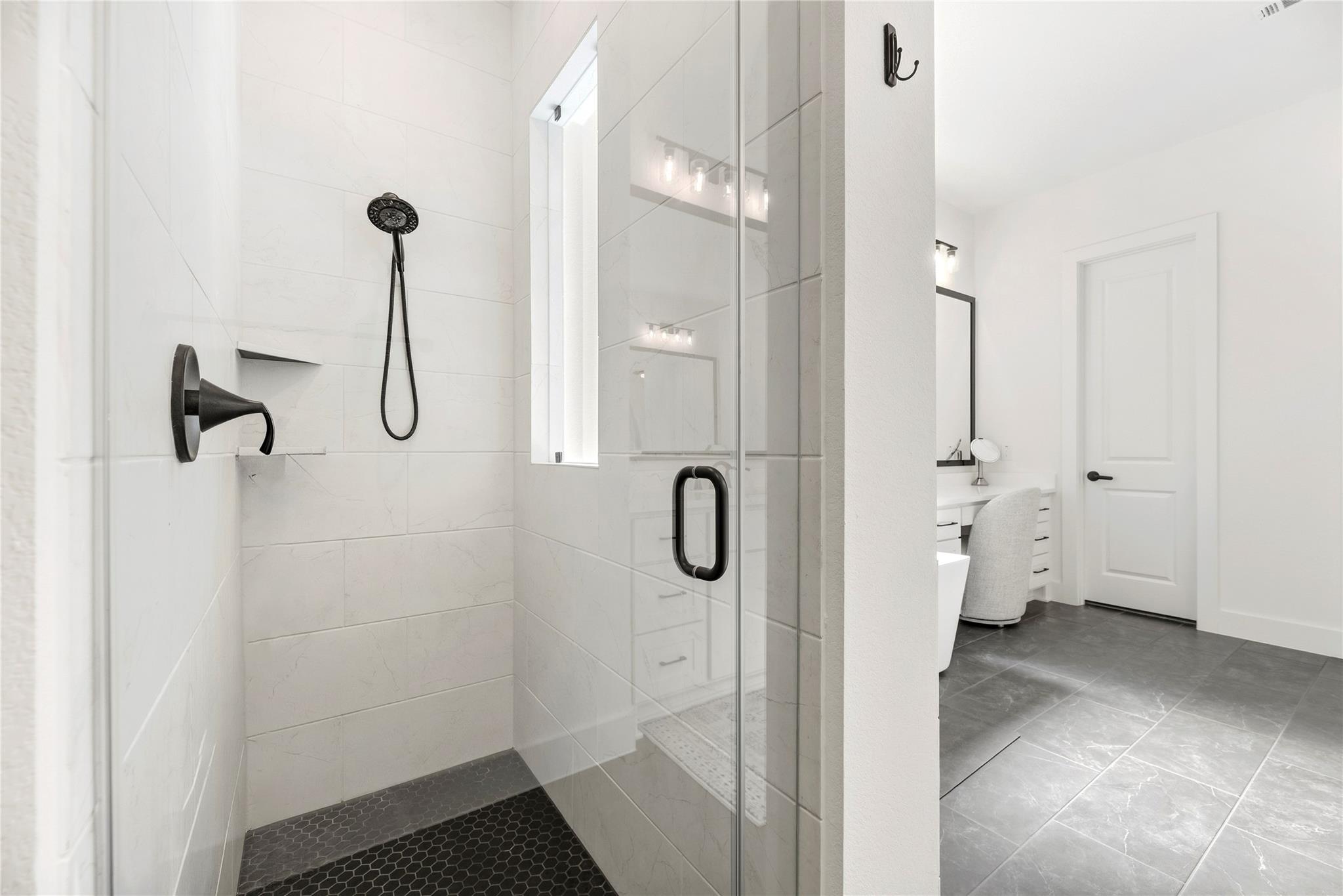 Modern bathroom with a glass walk-in shower, black fixtures, and a vanity area.