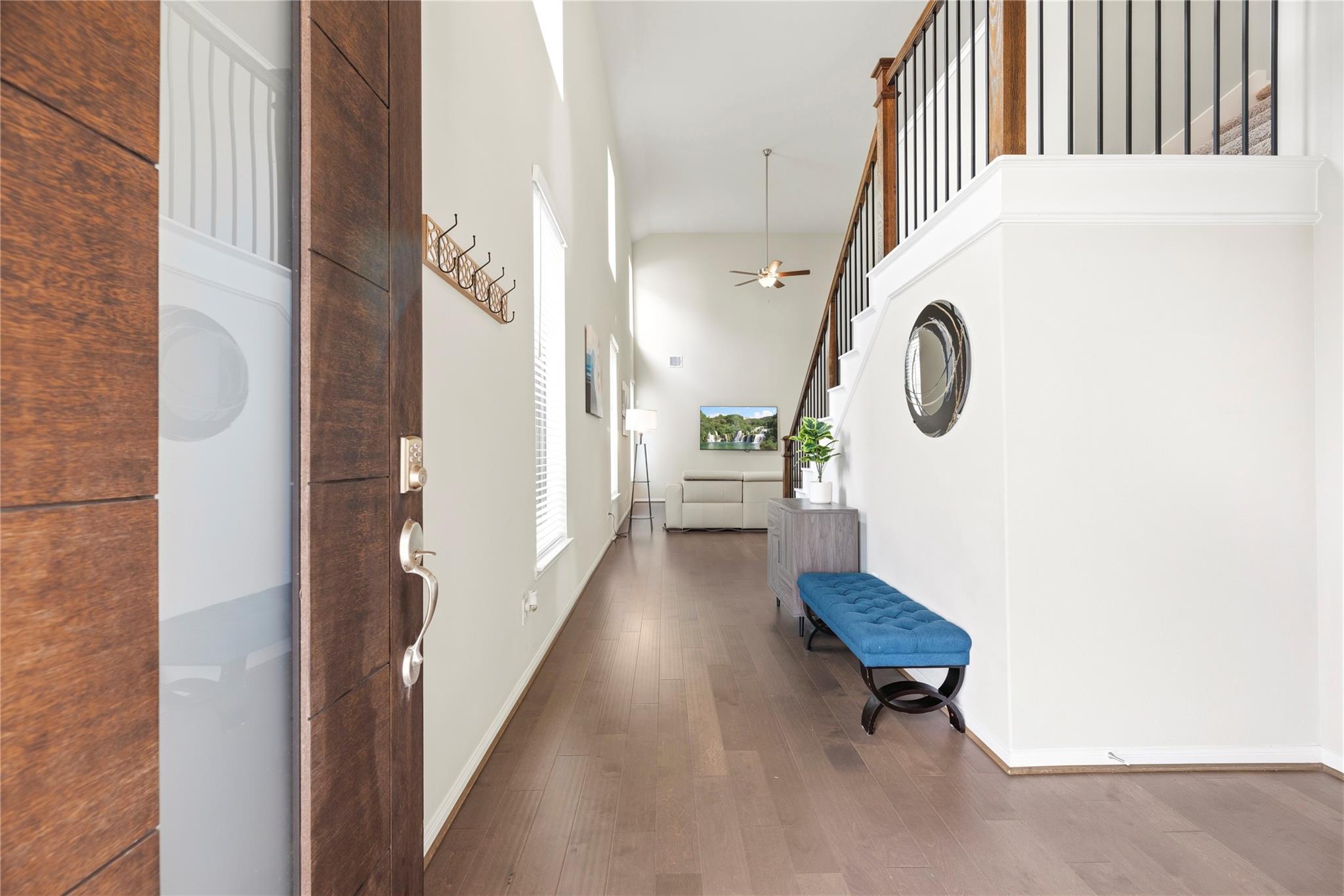 Furnished entry foyer with a tall staircase, dark wood door, and blue bench.
