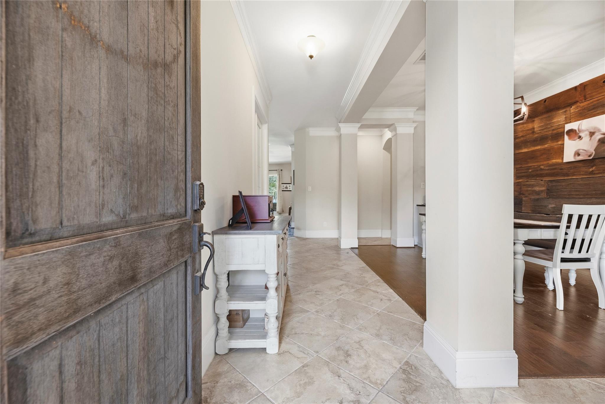 Entryway with a rustic wood front door, tiled floor, white columns, and adjoining dining area.