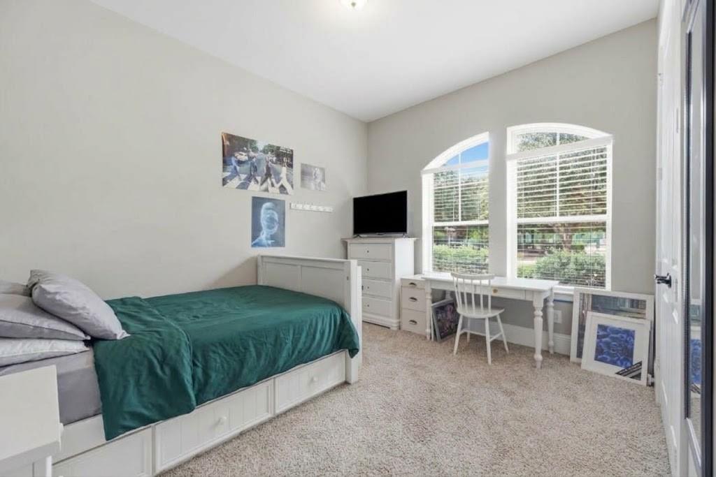 Bedroom with a teal-covered built-in bed and desk beneath arched windows.