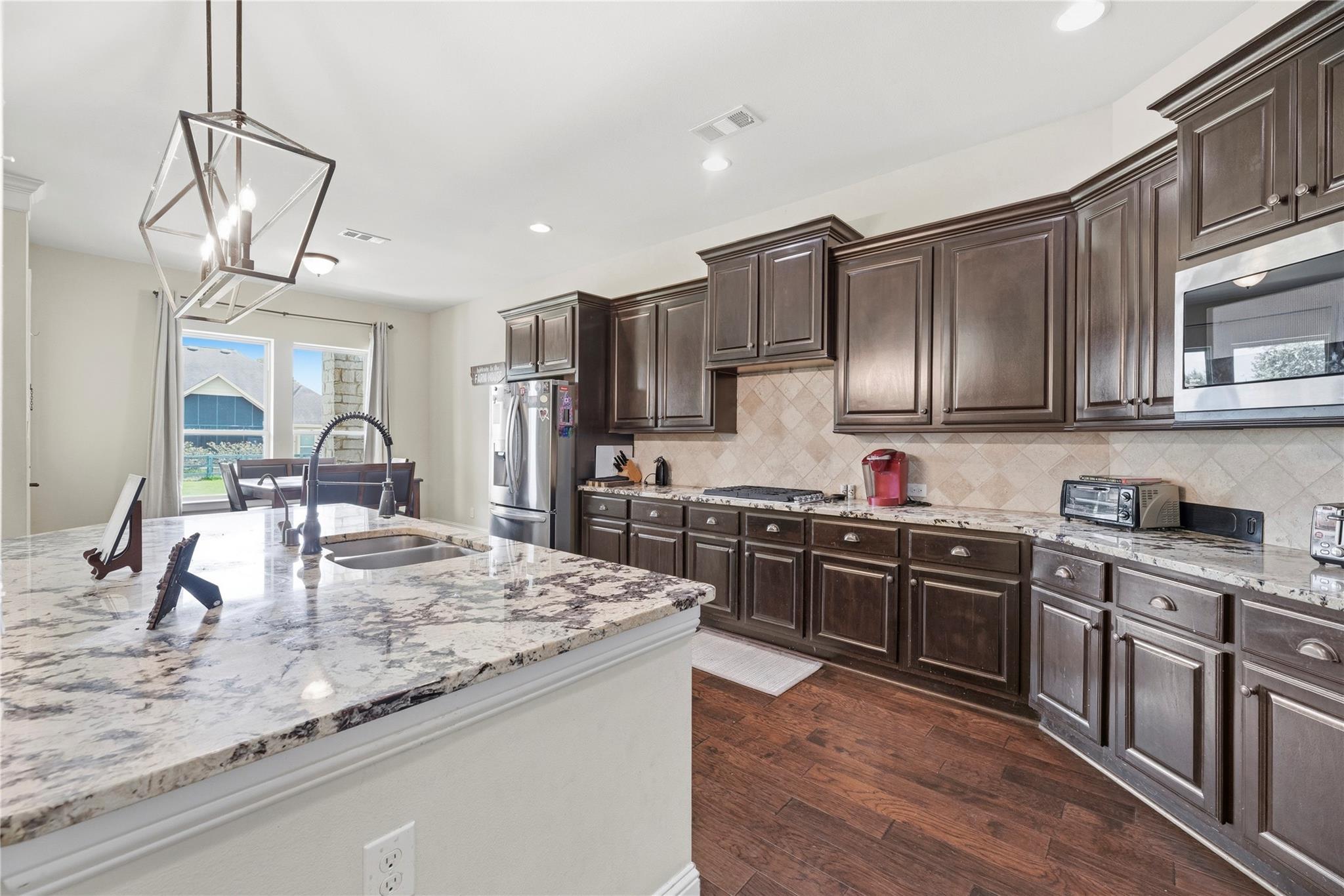 Kitchen with dark cabinetry, granite island and countertops, and stainless steel appliances.