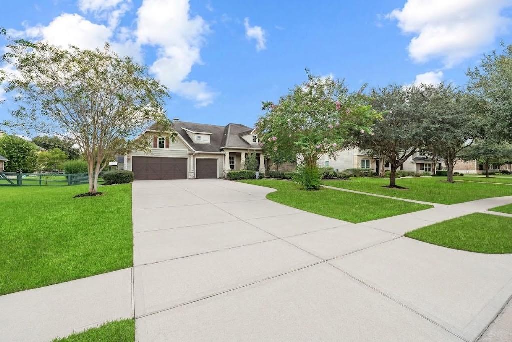 Two-story home with a double garage, broad driveway, and tree-lined lawn.