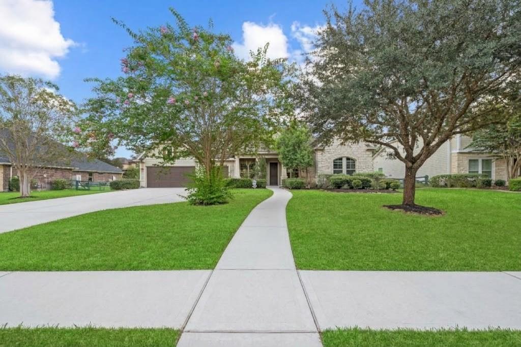 Stone house with a curved front walkway, broad lawn, and mature trees.