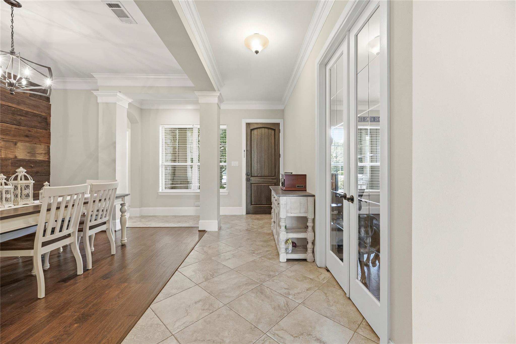 Home entryway with a dark wood front door, tiled floor, and adjoining dining area.