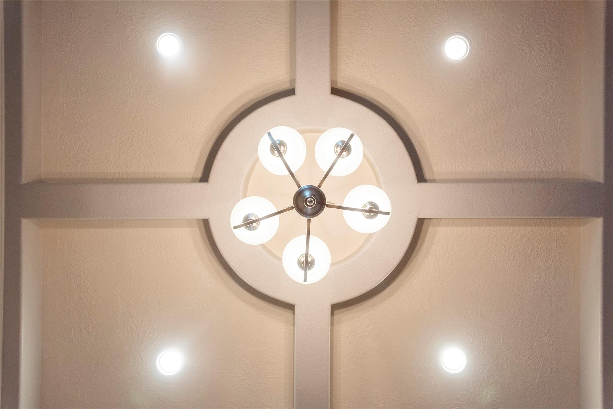 Five-light chandelier centered in a circular ceiling feature, surrounded by recessed lights.