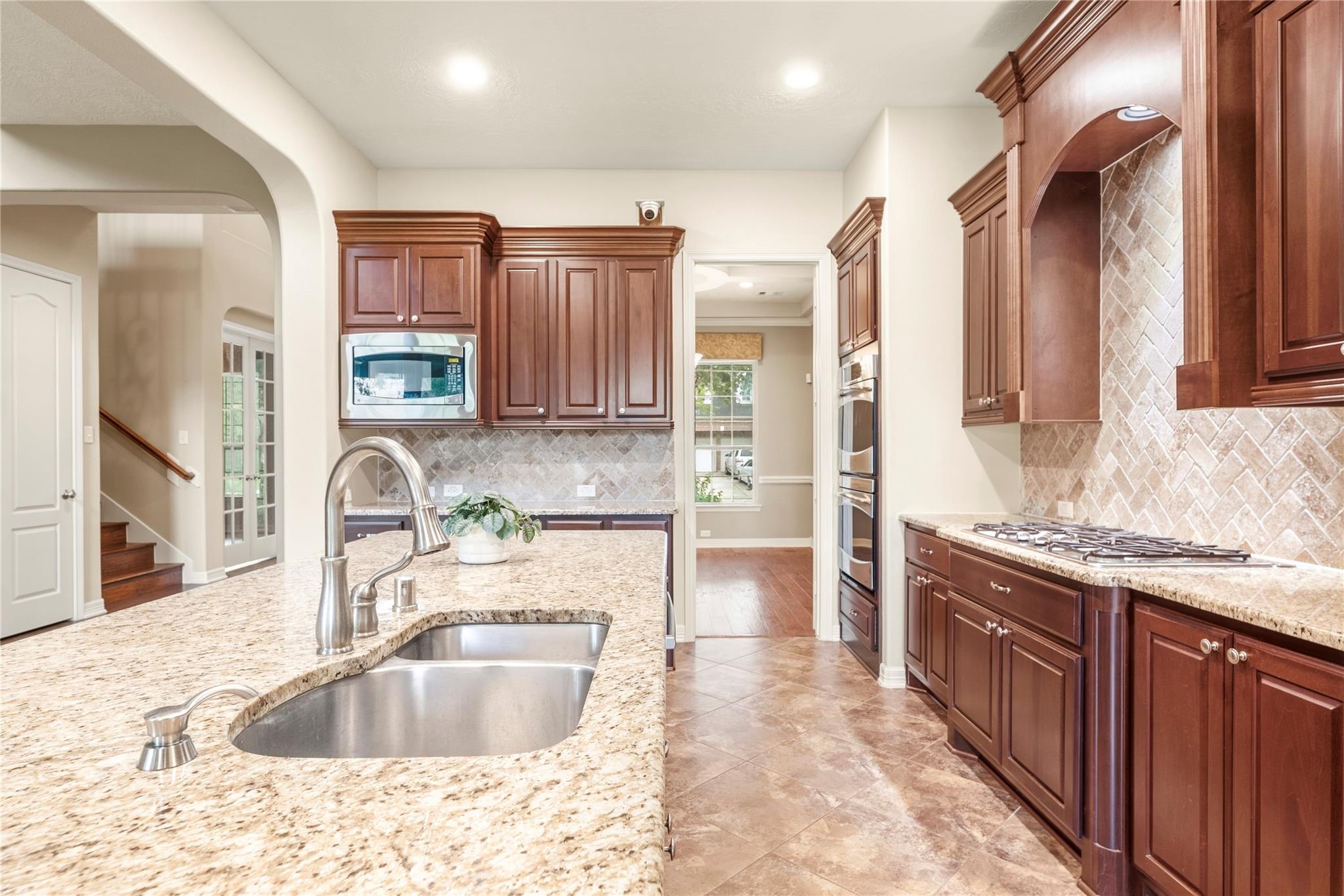 Kitchen with cherry cabinets, granite counters, a large sink, and a gas cooktop.