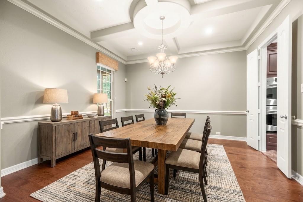 Dining room with a wooden table, upholstered chairs, chandelier, and tray ceiling.