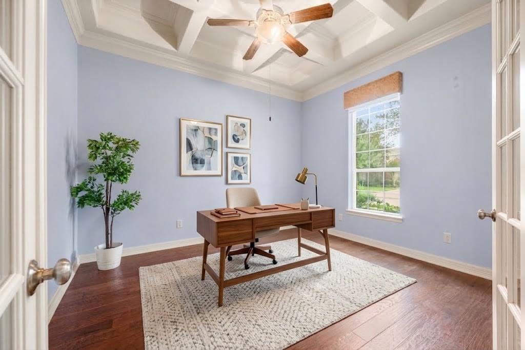 Home office with a wooden desk, pale blue walls, hardwood floors, and a coffered ceiling.