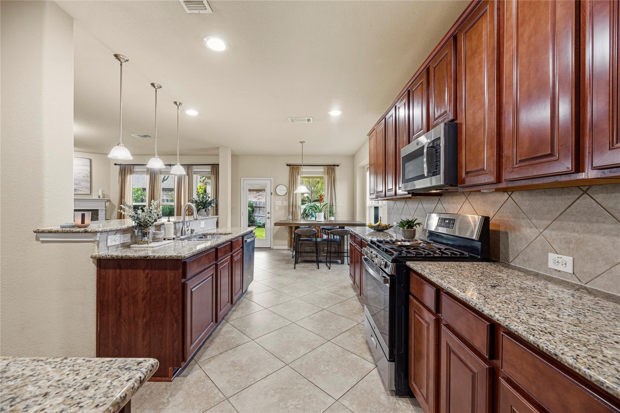 Kitchen with dark wood cabinets, granite counters, stainless steel range, and a central island.