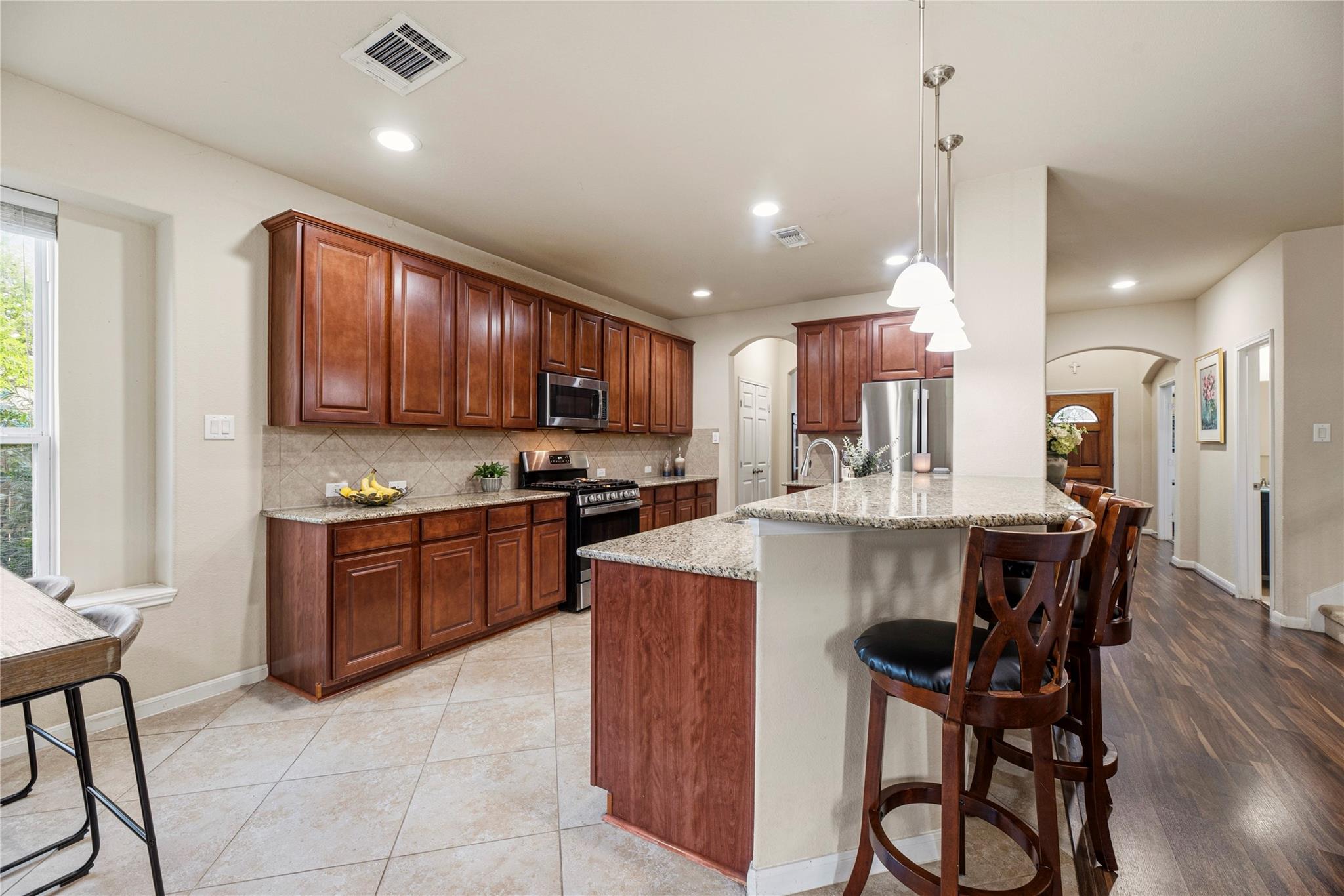 Kitchen with dark wood cabinets, granite island, stainless appliances, and wooden breakfast stools.