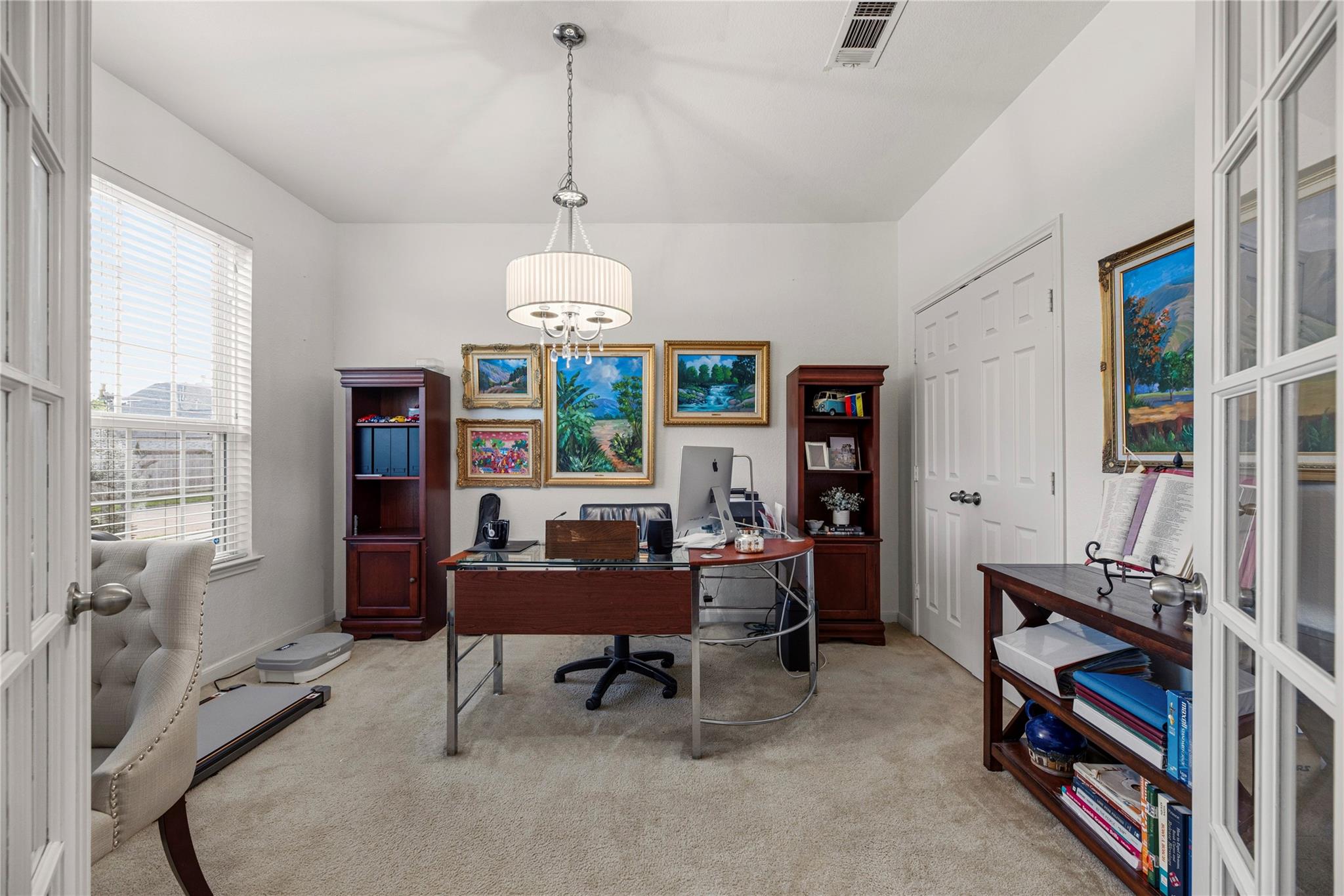 Furnished home office with a glass-topped desk, computer, and framed artwork.