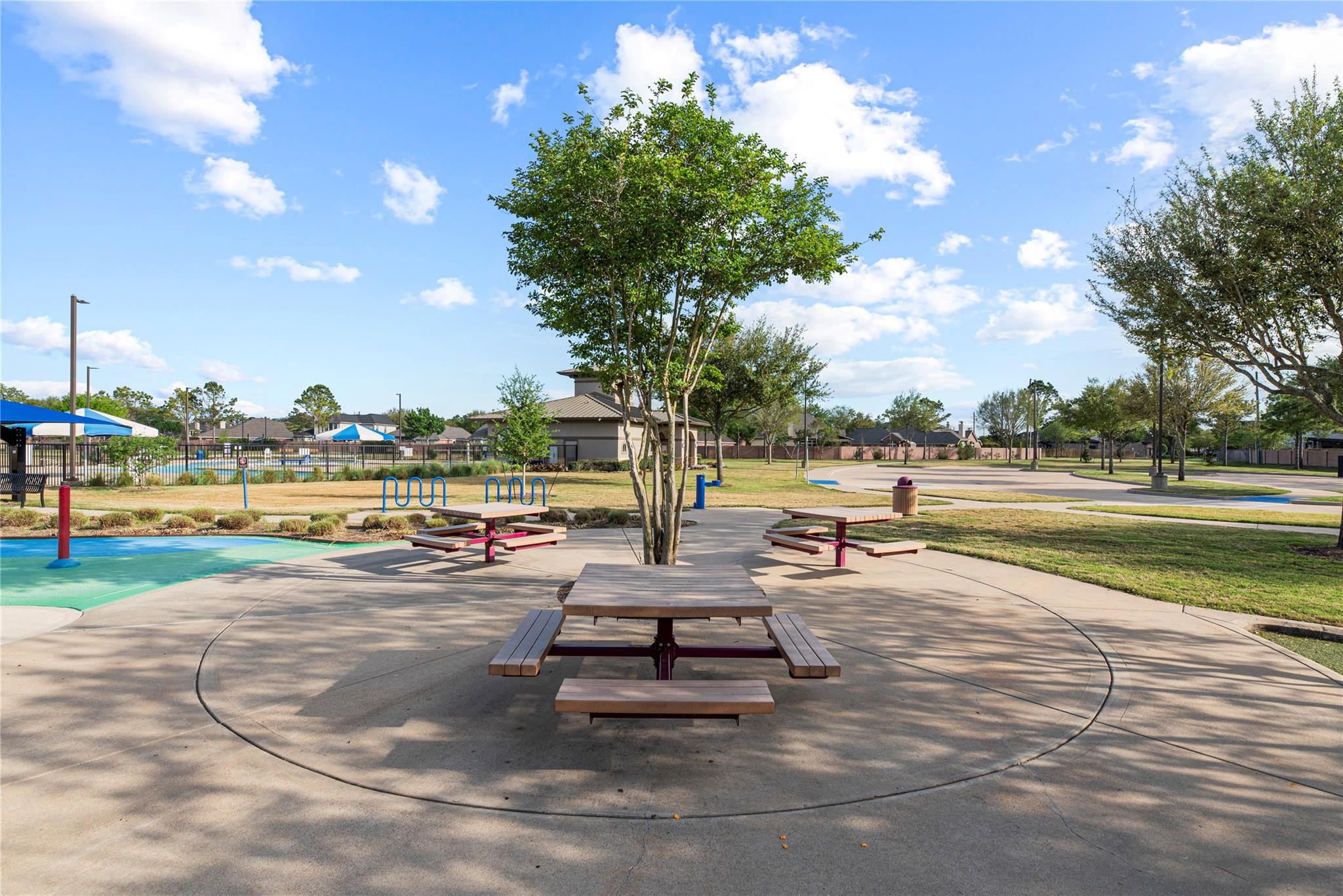 Community park with picnic tables, a splash pad, and a fenced pool.
