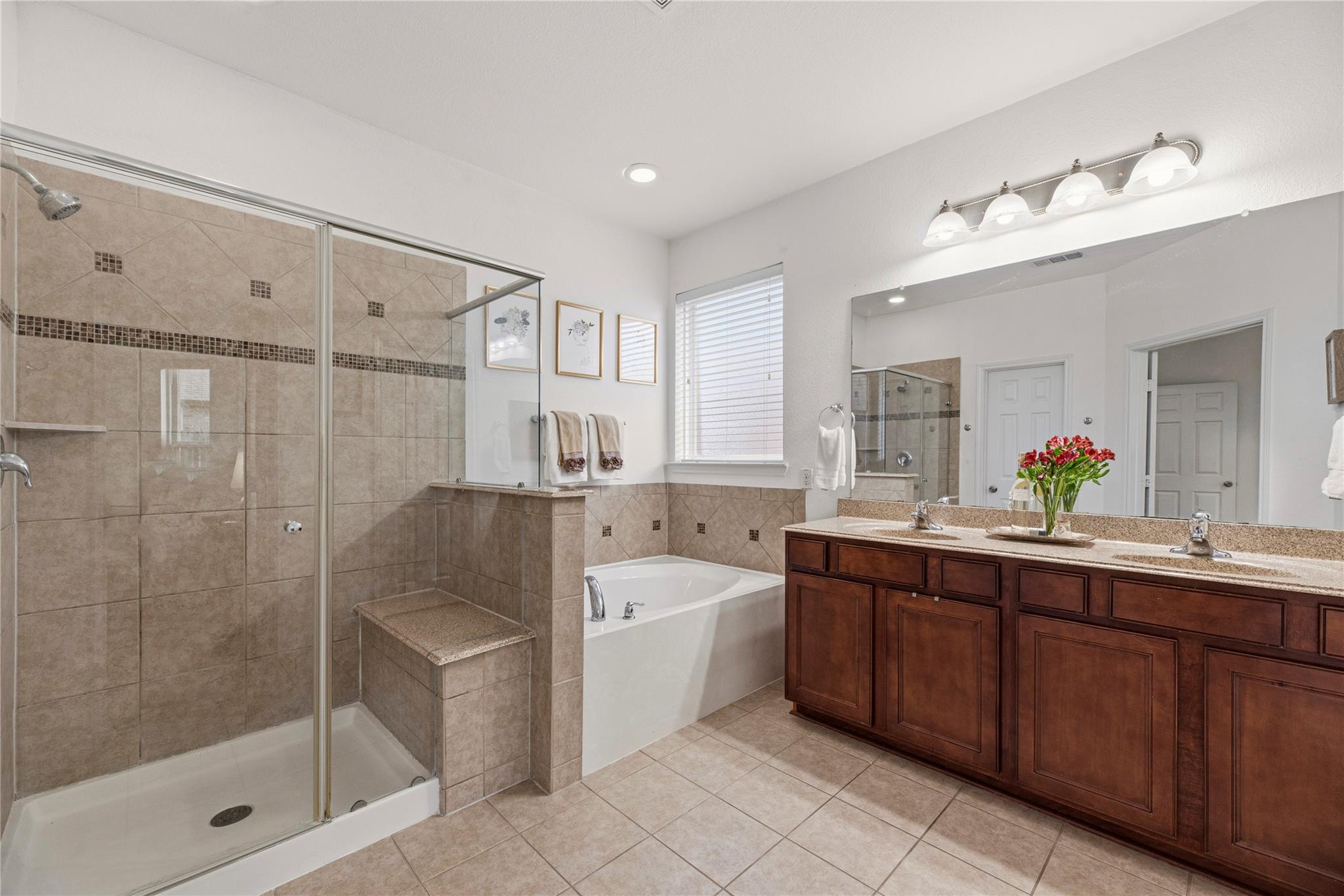 Primary bathroom with a glass shower, built-in soaking tub, and dark wood double vanity.