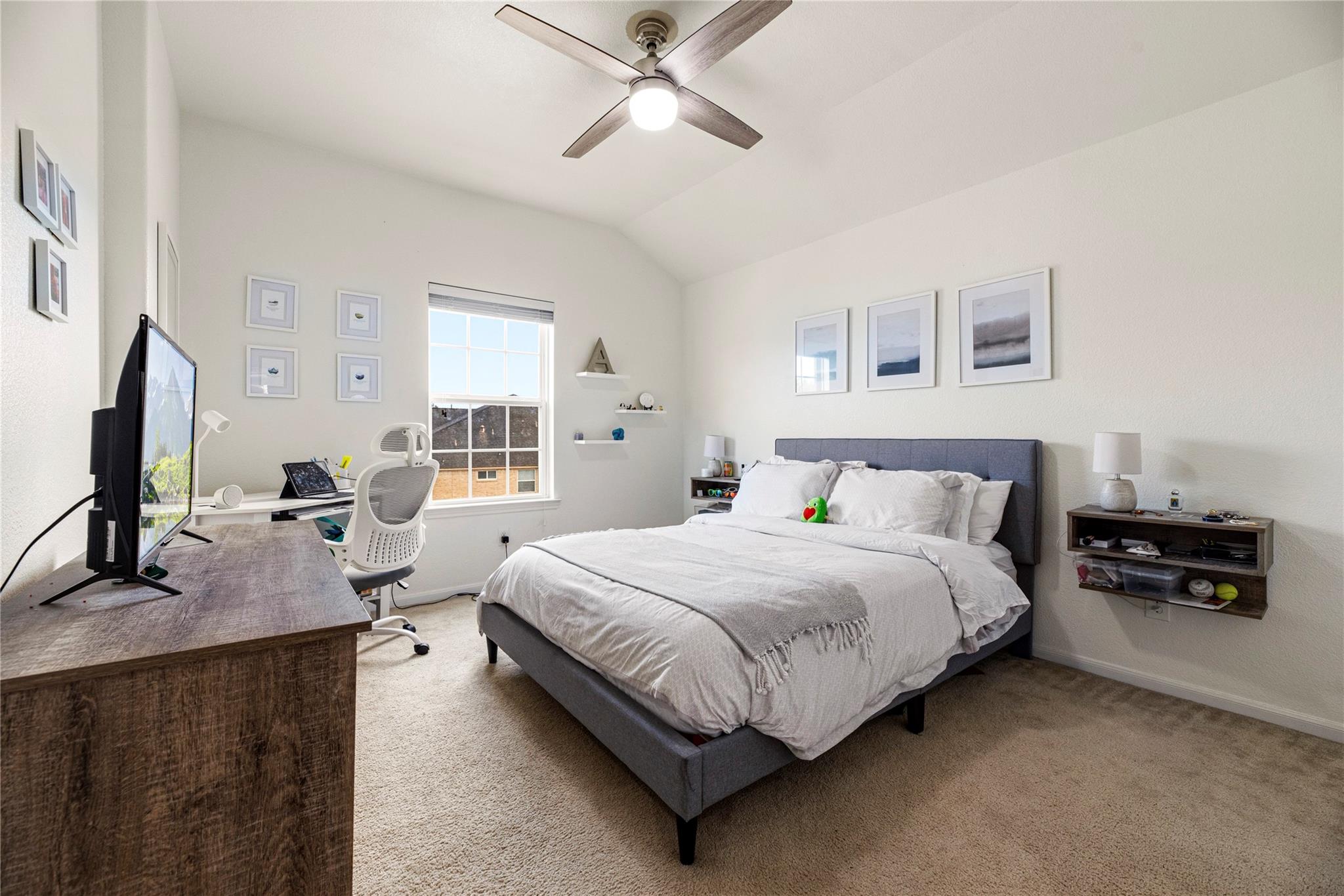 Bedroom with a gray bed, white bedding, and a desk workspace beside the window.