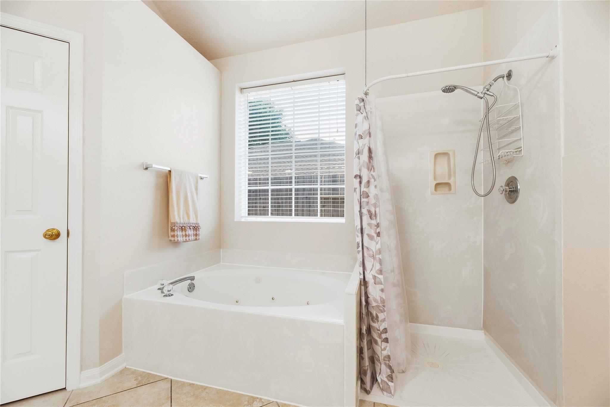 Bathroom with corner jetted tub and separate walk-in shower beside a window.