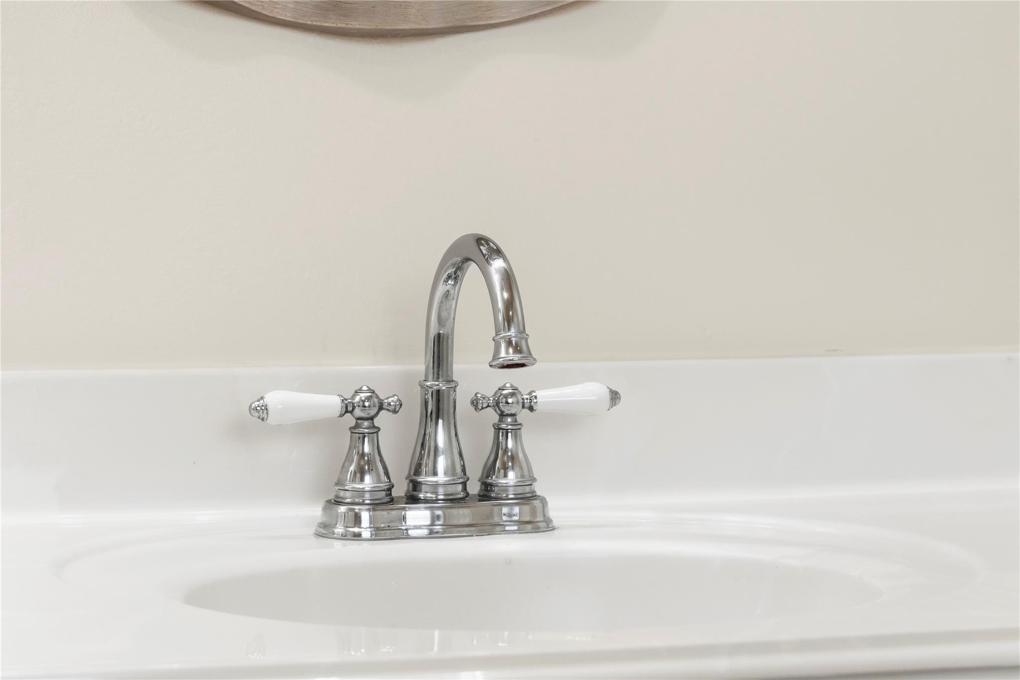 Bathroom sink with a polished chrome faucet and white handles.