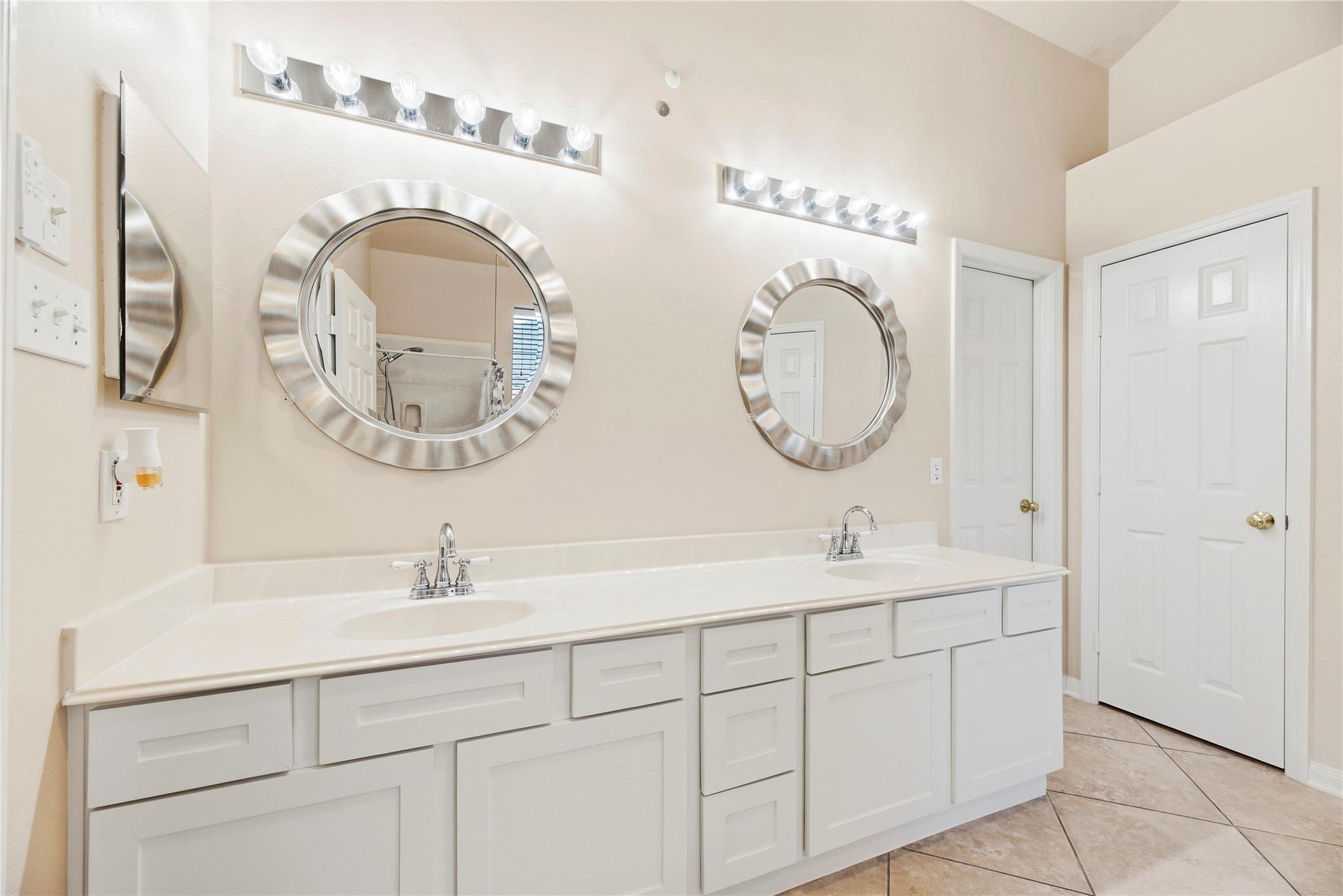 Bathroom with a long double-sink vanity and two round mirrors.