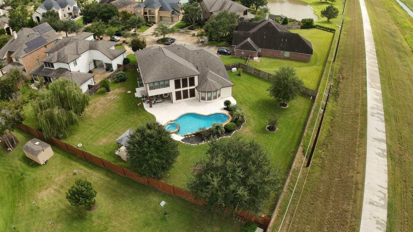 Aerial view of a two-story home with a curved pool and spacious fenced backyard.