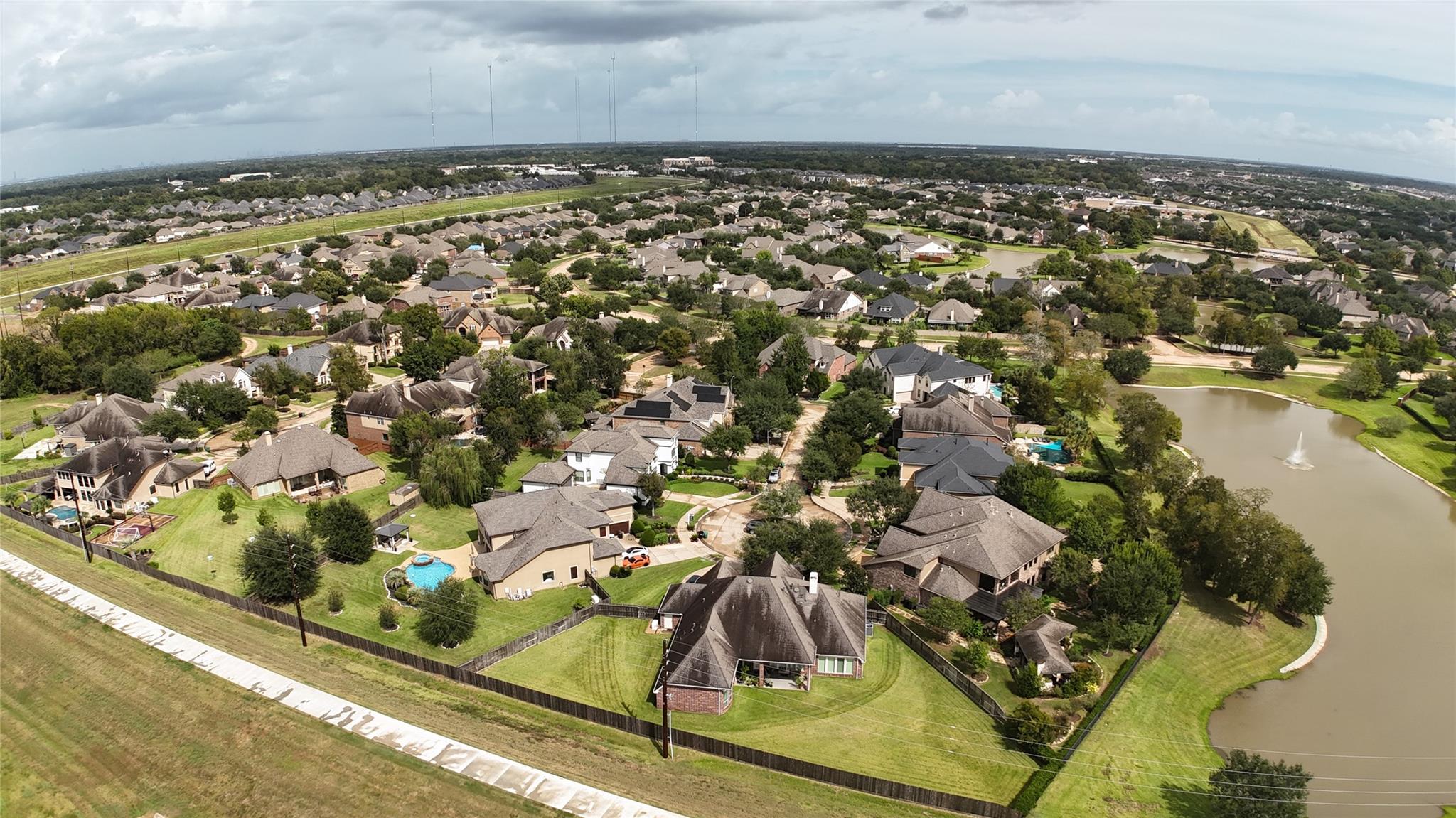 Aerial view of a residential neighborhood beside a pond with a fountain and landscaped yards.