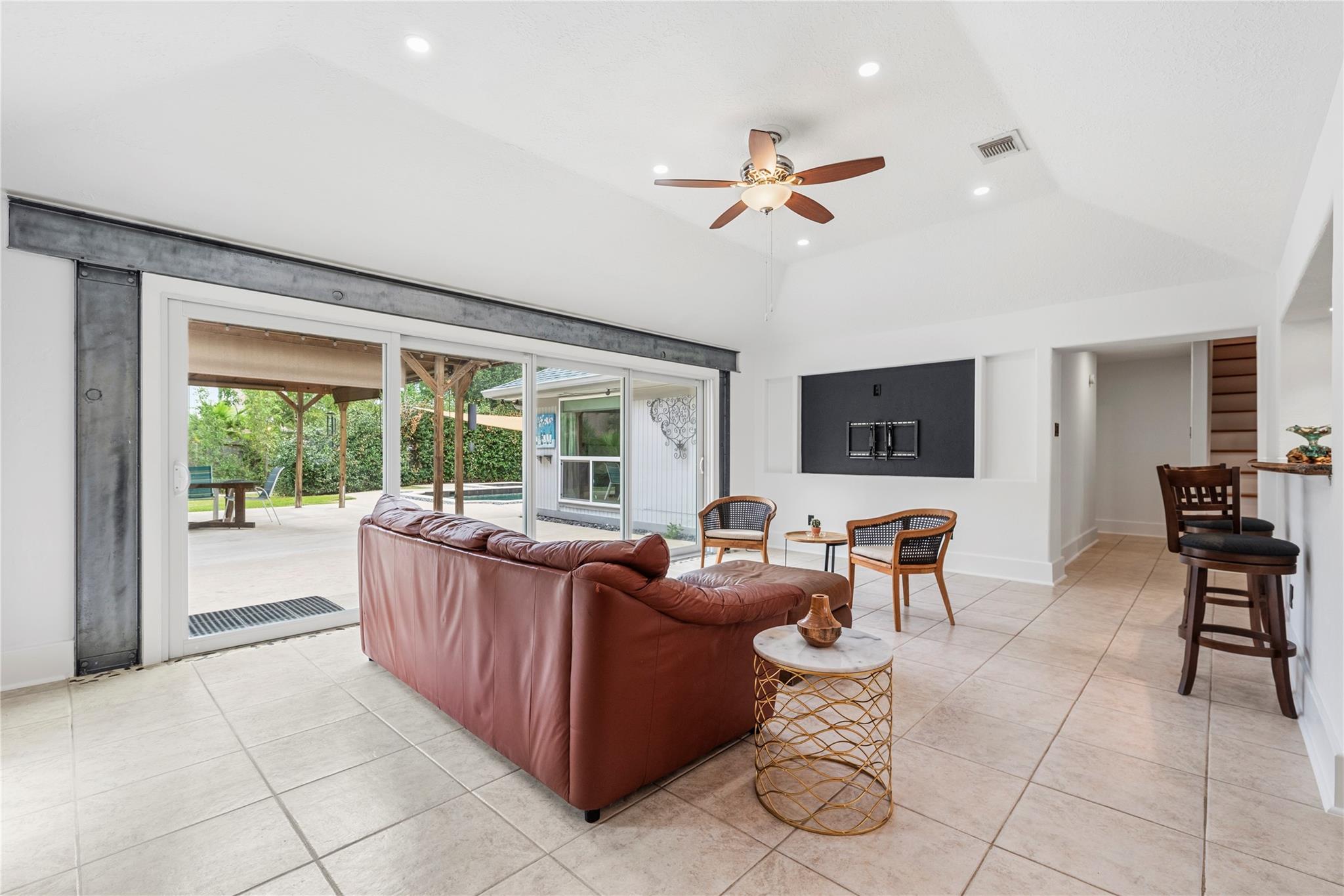 Living room with a brown leather sofa and sliding glass doors opening to a covered patio.