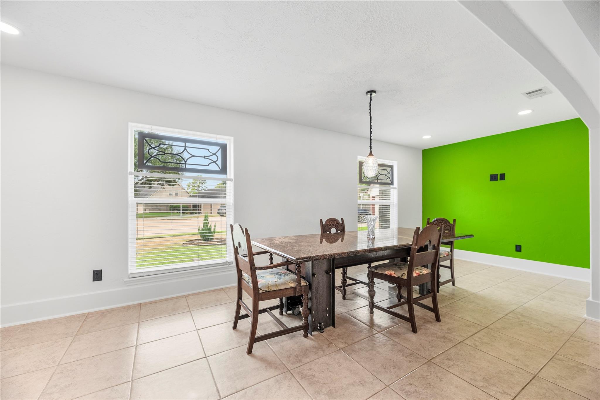 Dining room with a dark wood table, tiled floor, and bright green accent wall.