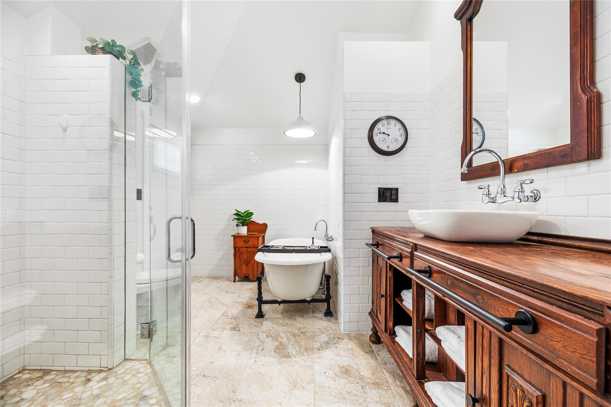 Bathroom with a freestanding tub, glass shower, and long rustic wood vanity.