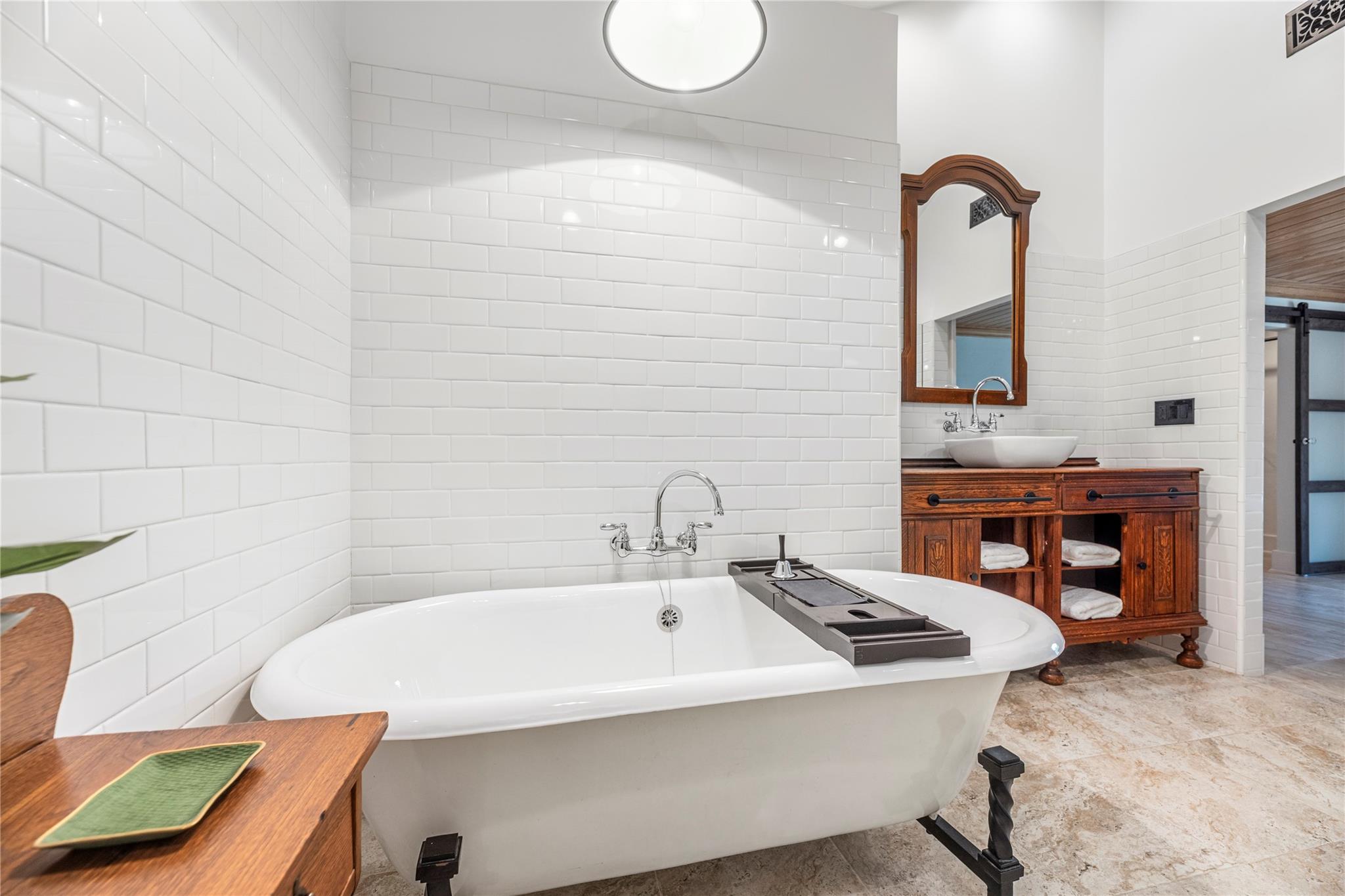 Bathroom with a freestanding tub and ornate wooden vanity with a vessel sink.