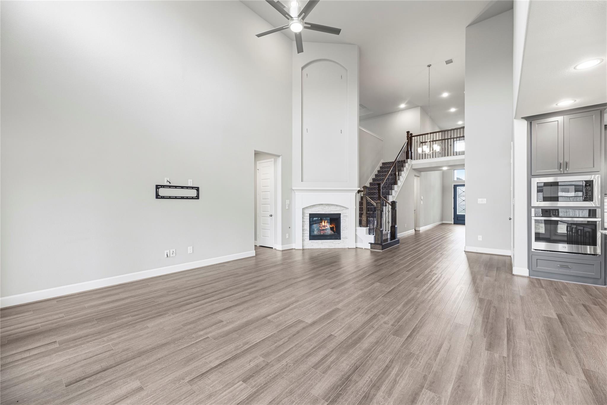 Open-plan living room with a tall ceiling, fireplace, and staircase beside the kitchen.