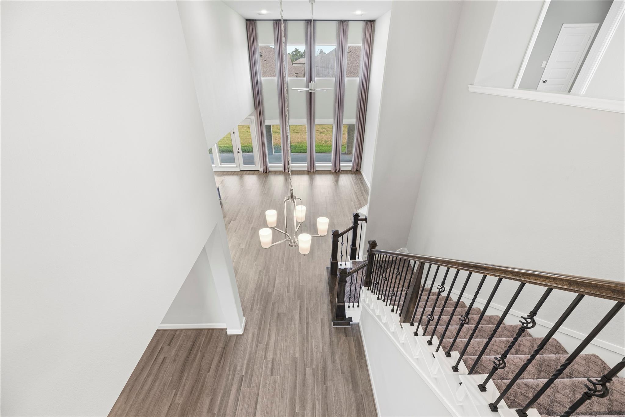 Two-story entry hall with a carpeted staircase, chandelier, and tall curtained windows.