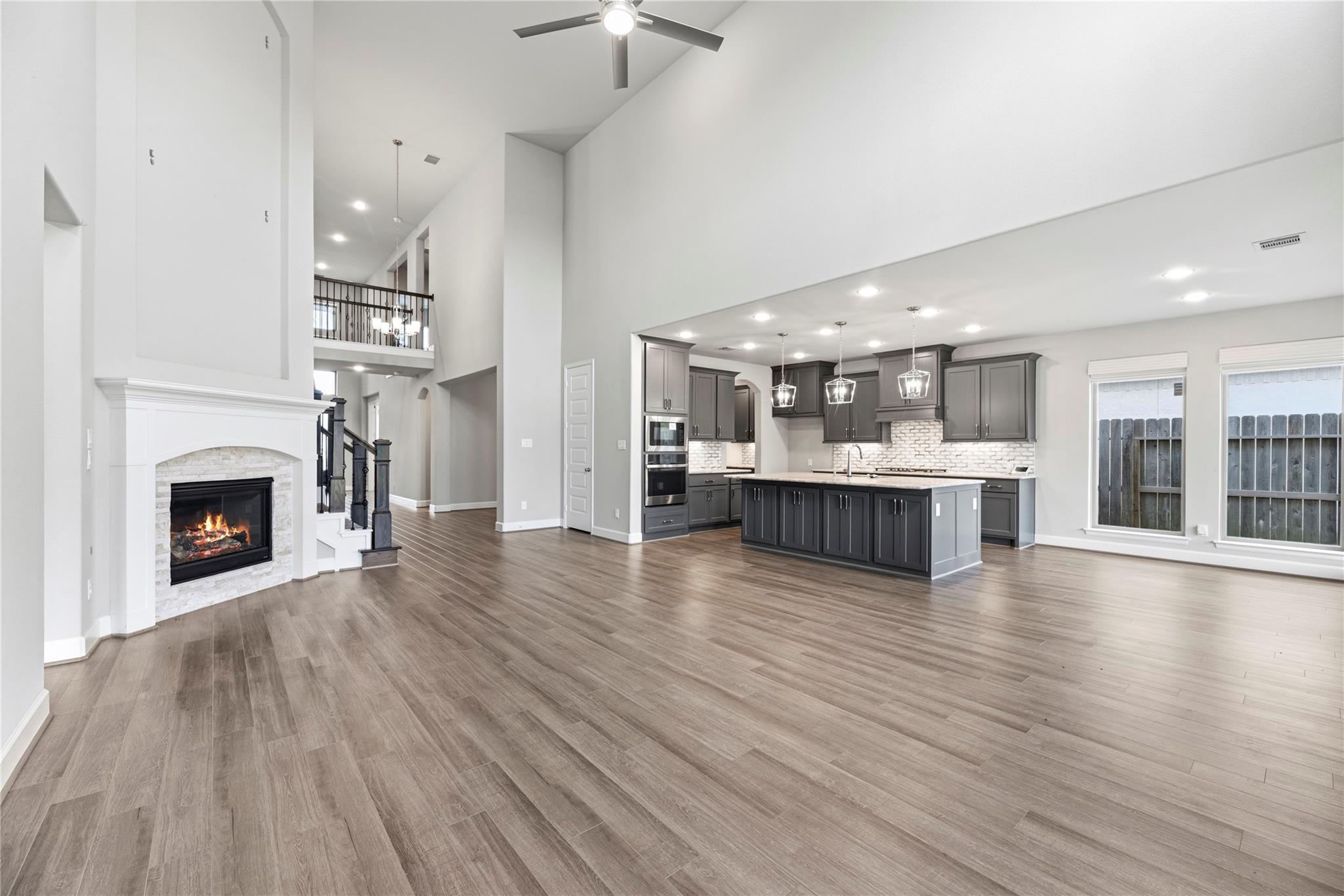 Open living room and kitchen with a vaulted ceiling, large island, and stone-surround fireplace.