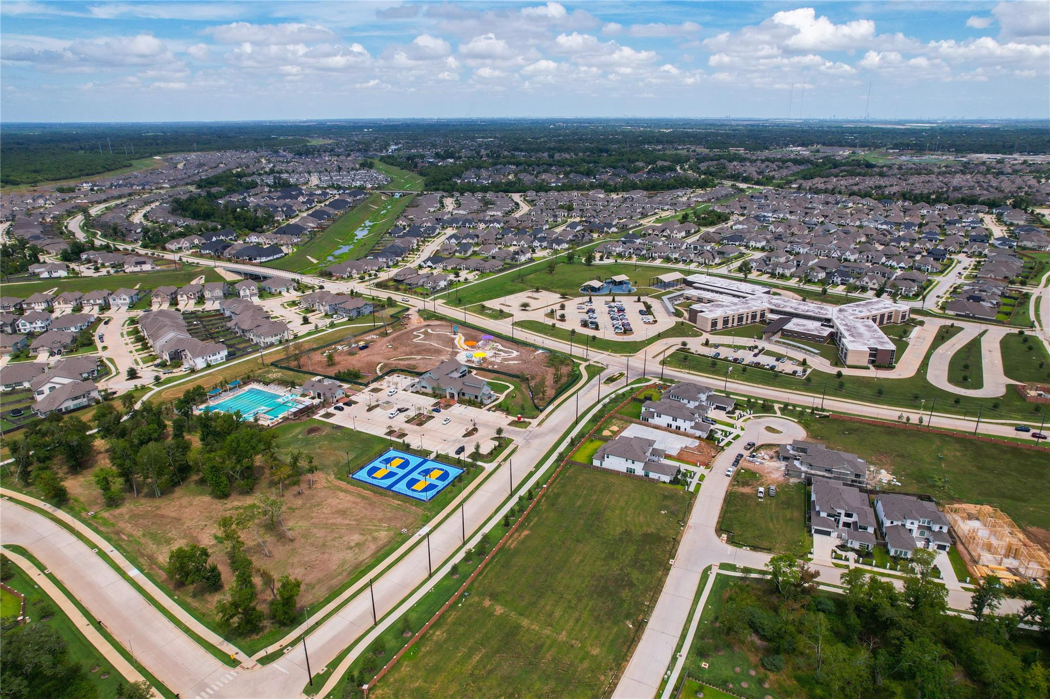 Aerial view of a residential community with a swimming pool and blue basketball courts.