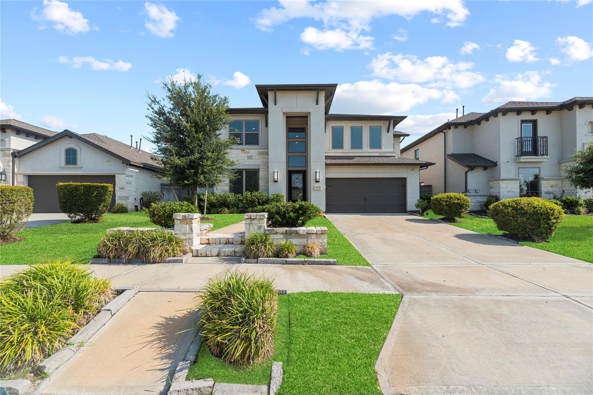 Two-story home with stone accents, landscaped front lawn, and wide driveway.