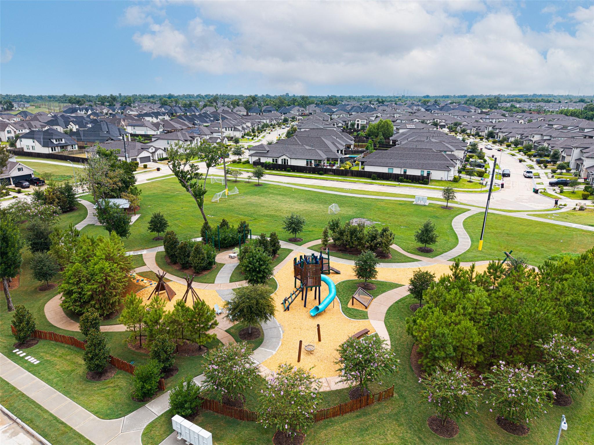 Aerial view of a neighborhood park with winding paths and a playground amid surrounding homes.