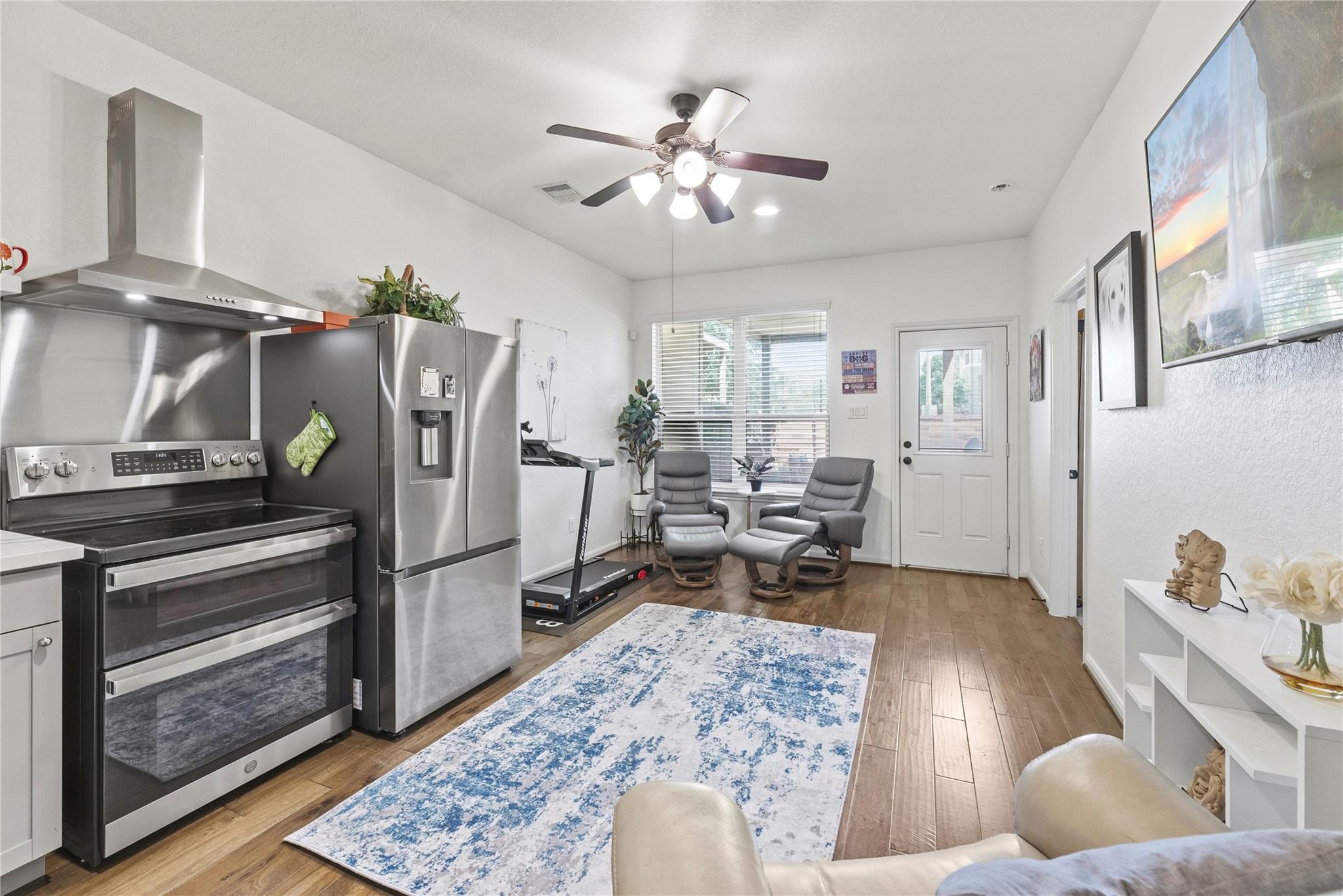 Open-plan kitchen and living area with stainless appliances, recliners, and a blue-and-white rug.