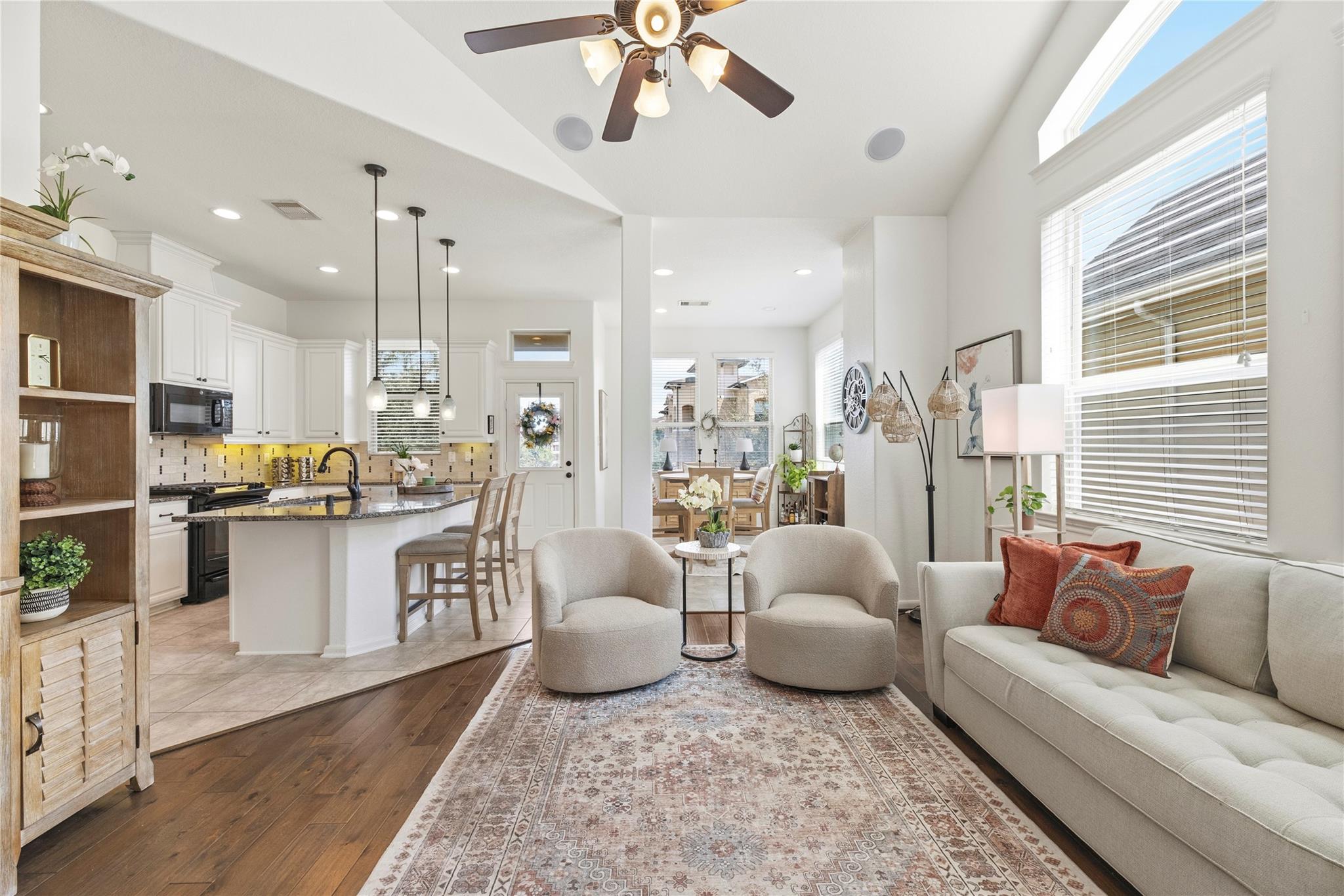 Open-plan living room and kitchen with a white sofa, armchairs, and a large window.