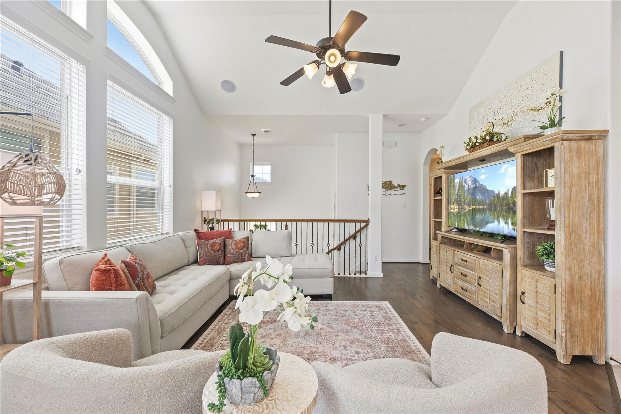 Bright living room with a vaulted ceiling, tall windows, and a large sectional sofa.