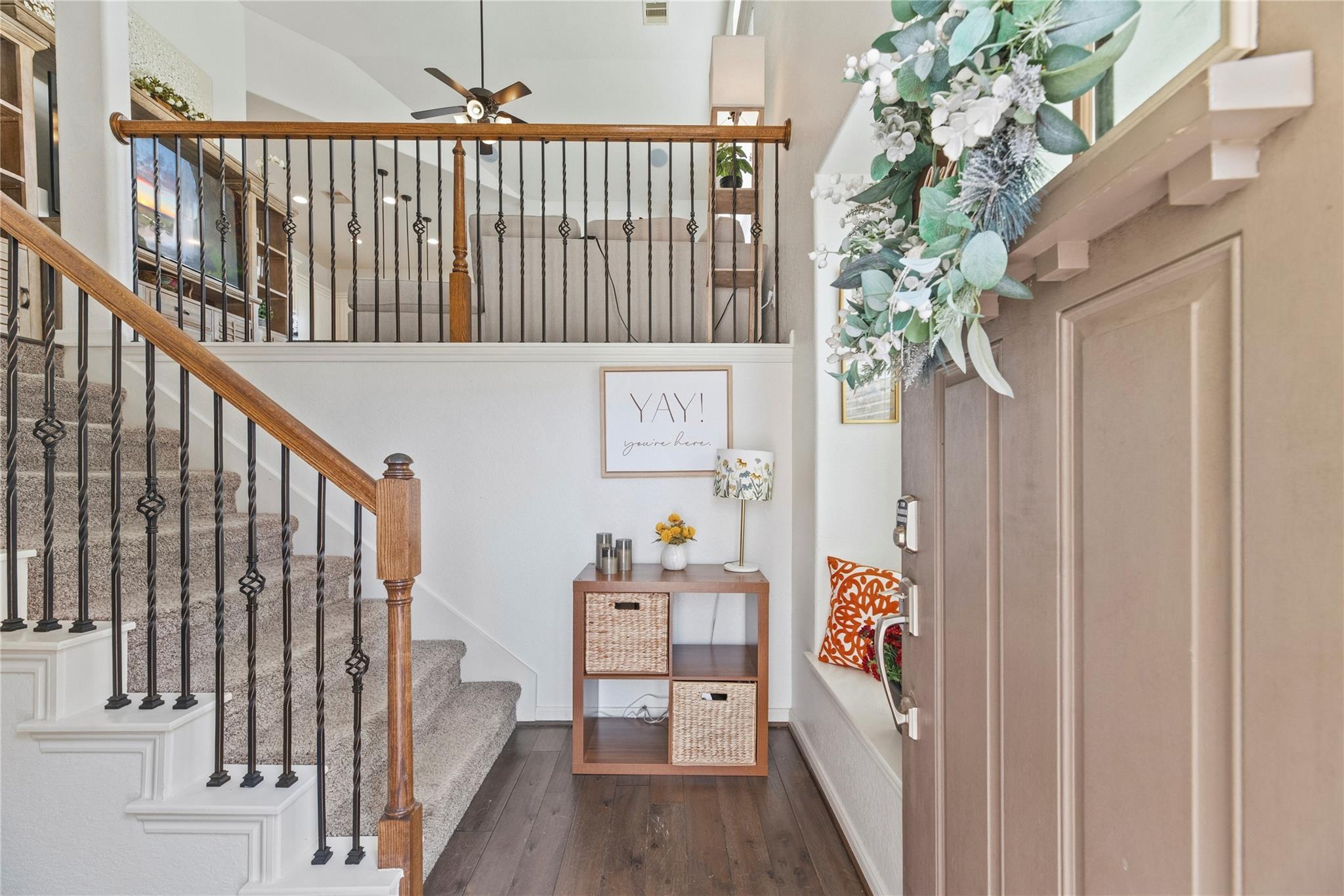 Entryway with carpeted staircase, wood console table, and wreath on the front door.