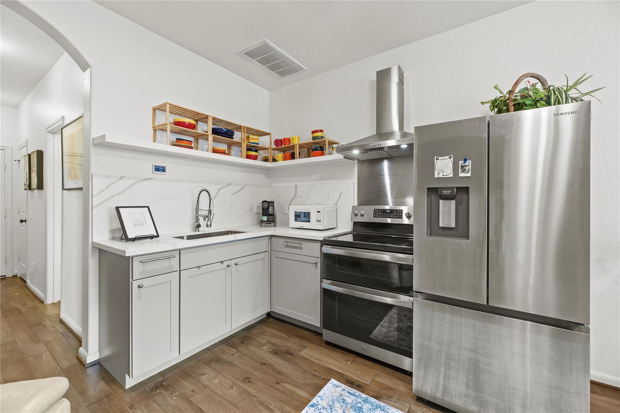 Bright kitchen with white cabinets, veined backsplash, and stainless steel appliances.