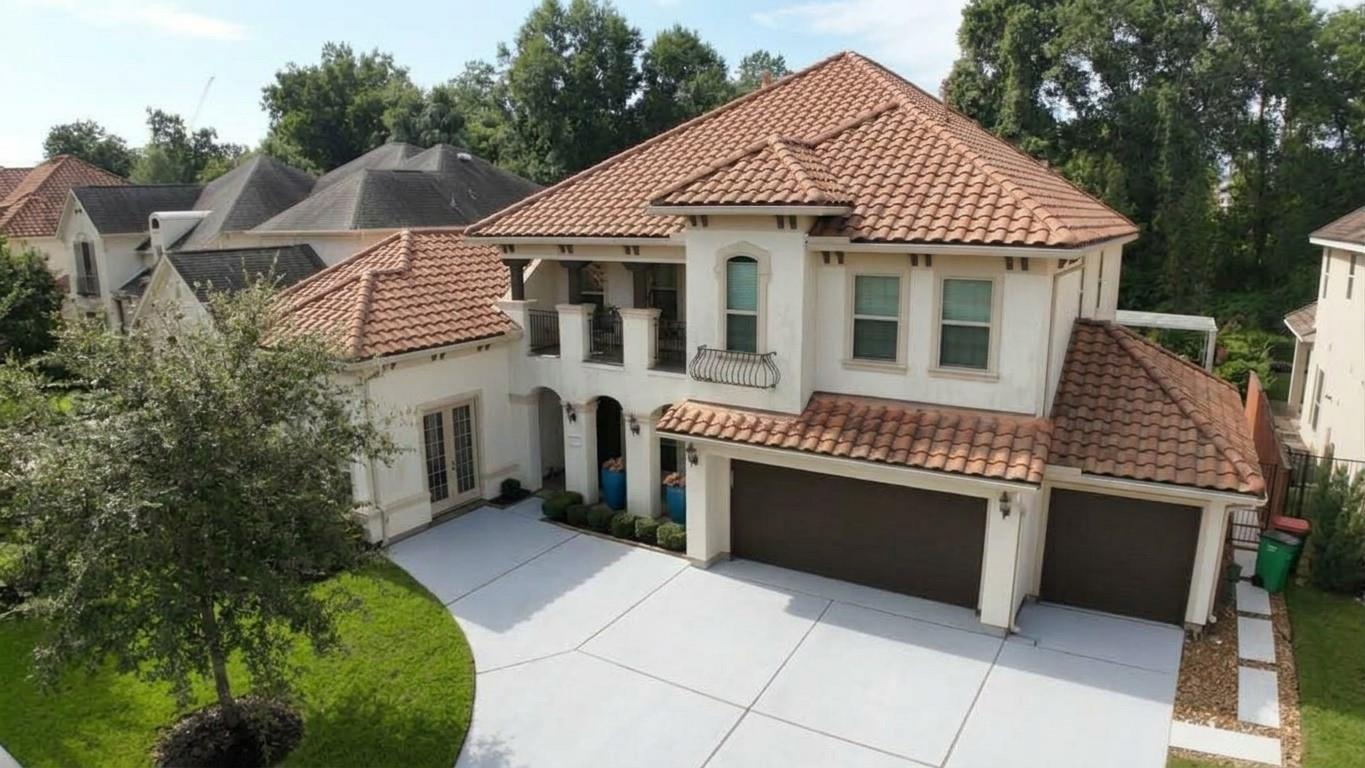 Two-story stucco home with terracotta roof, covered balcony, and three-car garage.