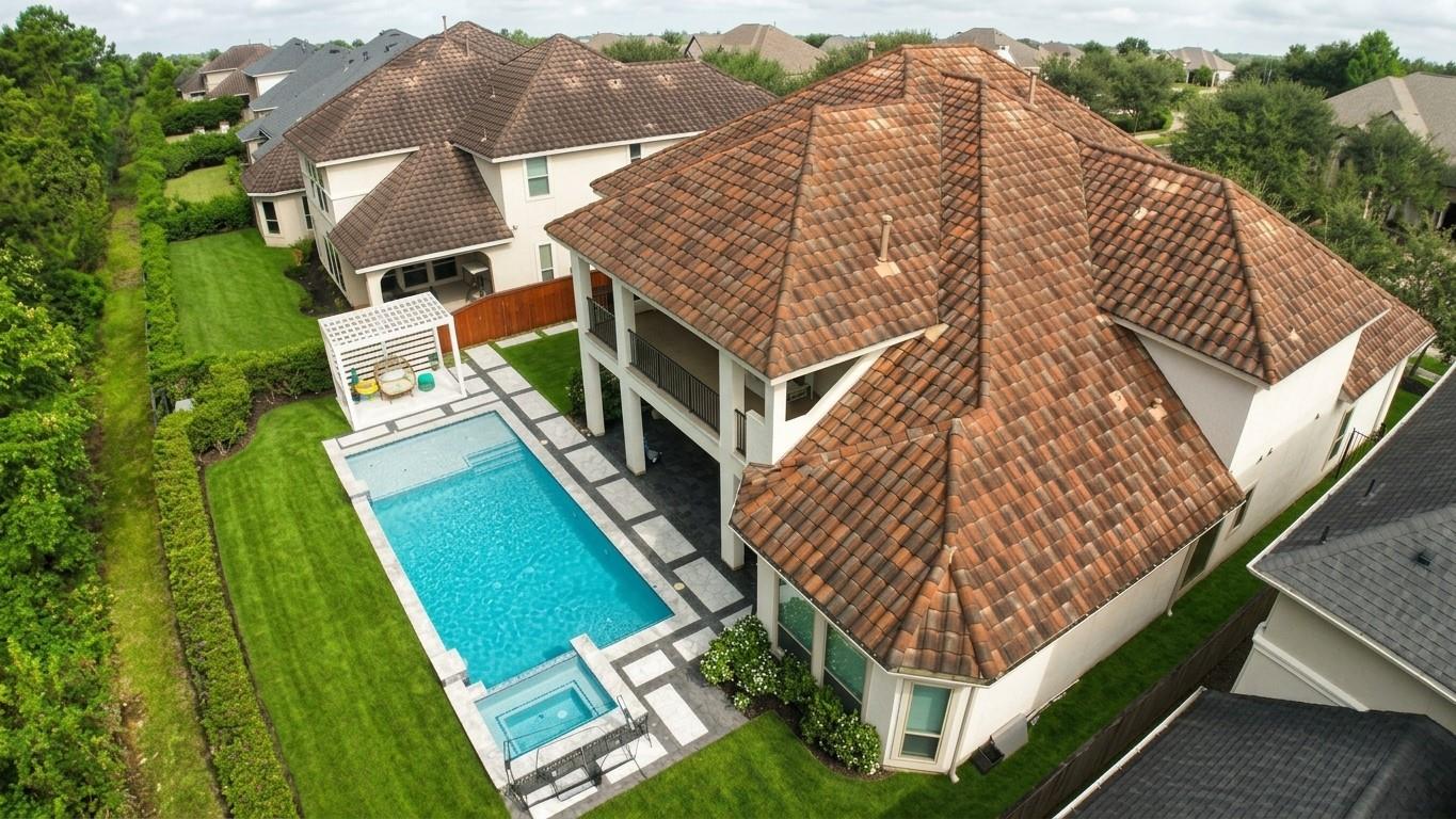 Aerial view of a two-story home with a backyard pool and tiled roof.